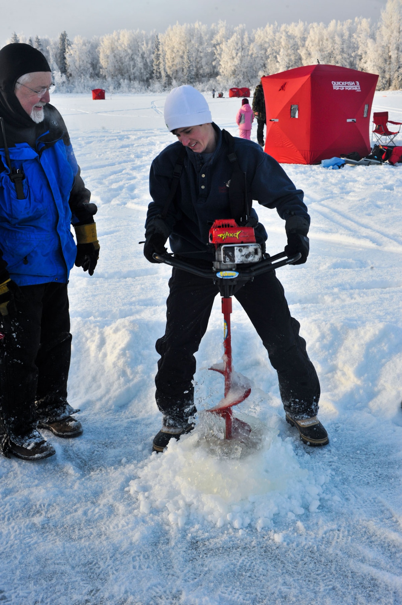 Sarah Mueller, a Hillberg employee, drills an ice fishing hole for a family during the JBER annual Ice fishing tournament Jan. 8.  (U.S. Air Force photo/A1C Jack Sanders)
