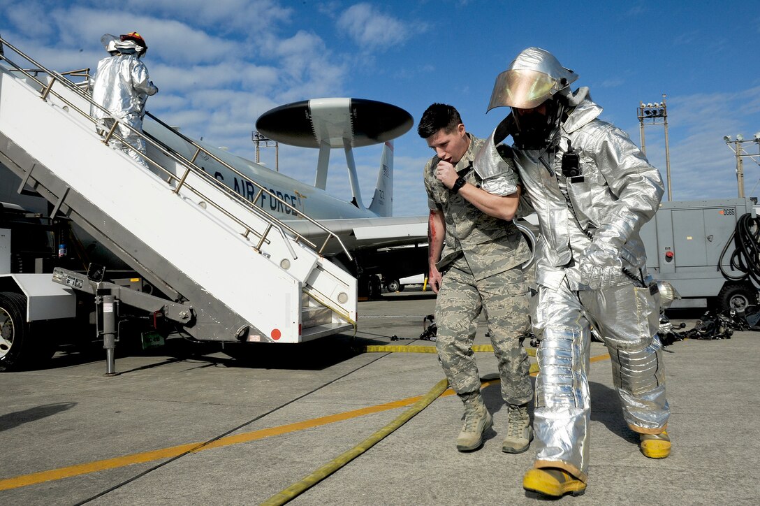 A firefighter from the 18th Civil Engineer Squadron helps a "victim" from an E-3 Sentry "engine fire" Jan. 19, 2011, move away from the scene at Kadena Air Base, Japan.  The "fire" was during a local operational readiness exercise. (U.S. Air Force photo/Staff Sgt. Jonathan Steffen)