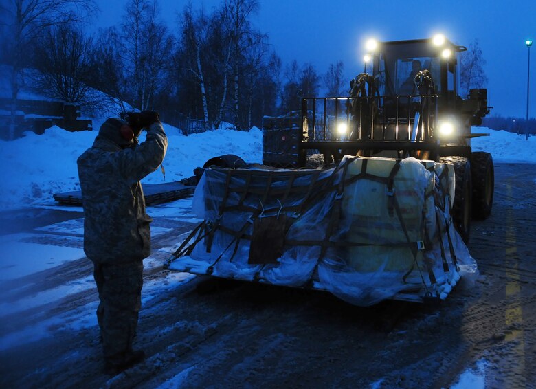 Tech. Sgt. Carlos Cardenas guides a forklift being driven by Senior Airman Scott Knight Jan. 7, 2011, at Lithuania Air Force Air Base in Lithuania. Sergeant Cardenas and Airman Knight are assigned to the 493rd Expeditionary Fighter Squadron Redeployment Action Team at Royal Air Force Lakenheath, England. (U.S. Air Force photo/Staff Sgt. Stephen Linch)