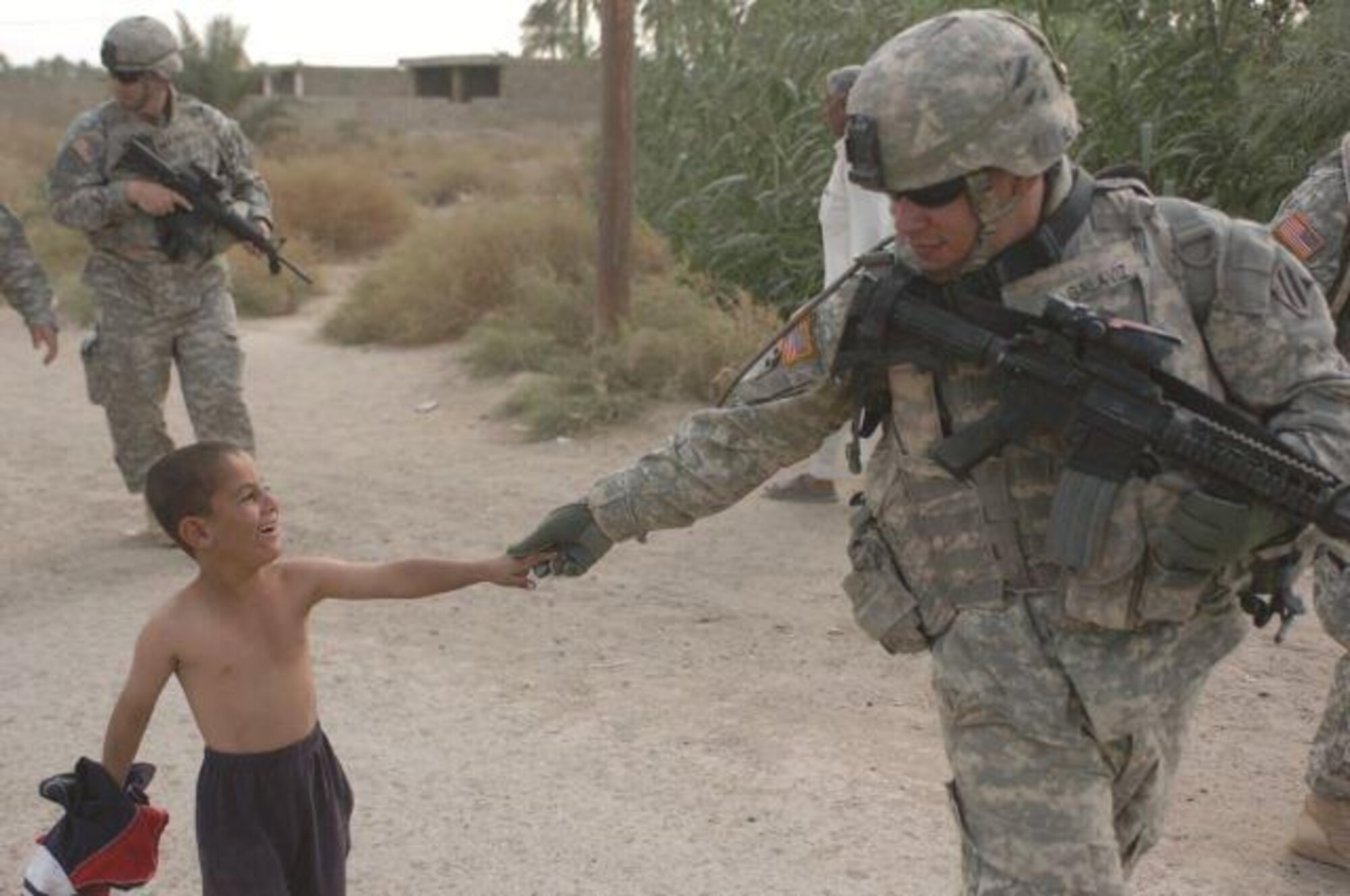 HAWR RAJAB, Iraq -- Despite a language barrier, an Iraqi child greets a Soldier escorting Maj. Gen. Rick Lynch, 3rd Infantry Division commander, at Fort Stewart, Ga., back from a meeting with the Concerned Citizens Program in Hawr Rajab, Iraq, Oct. 17, 2007. (Army file photo)