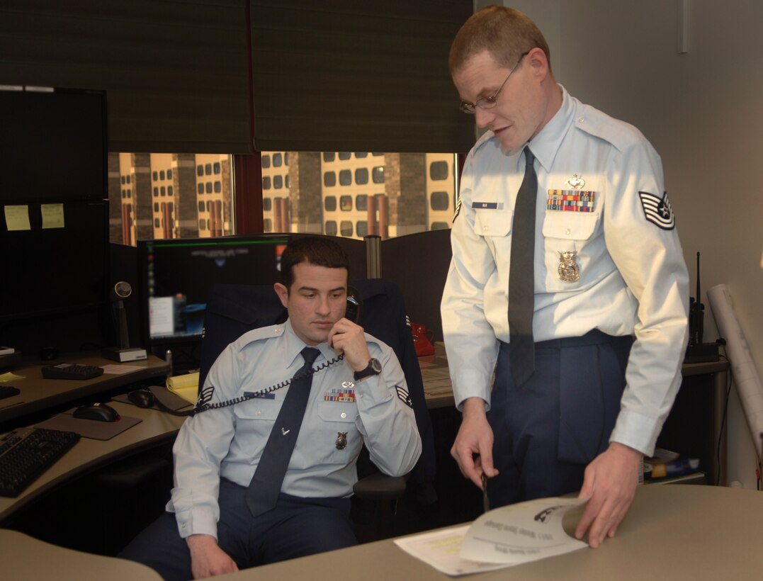 Senior Airman Craig George, 28th Civil Engineer Squadron fire department Enhanced-911 dispatcher, answers a call as Tech. Sgt. Joseph Nix, 28th CES fire department NCO in charge of the E-911 dispatch center, guides him with information pertaining to a question at Ellsworth Air Force Base, S.D., Jan. 10, 2011.  Airman George and Sergeant Nix help ensure the safety of Ellsworth team members by responding to emergency calls. (U.S. Air Force photo/Airman 1st Class Alessandra N. Hurley)