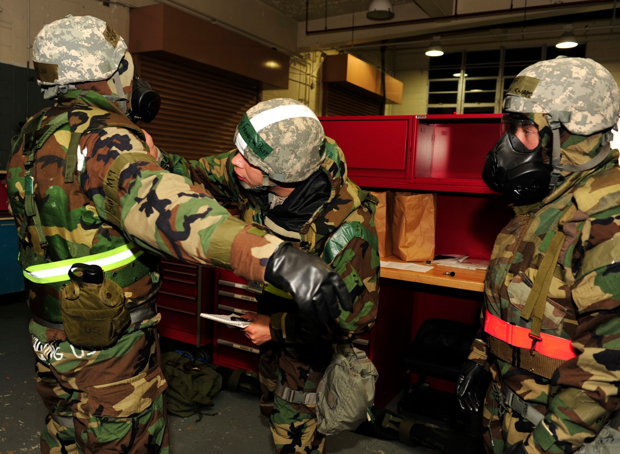 Staff Sgt. Franklin Palfy, an Exercise Evaluation Team member, inspects Tech. Sgt. Jerry Davison (left) and Airman 1st Class John Knapp (right) for proper wear of Mission Oriented Protective Posture gear during Beverly High 11-02, a local operational readiness exercise, at Kadena Air Base Jan. 20. Sergeants Palfy and Davison and Airman Knapp are all members of the 18th Equipment Maintenance Squadron. (U.S. Air Force photo/Staff Sgt. Lakisha A. Croley) 