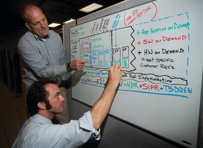 Bob Rozard, left, and Trey Oats diagram the network connections on a white board during the successful CS/C2 data exchange technology development and experimentation as SSC Atlantic.