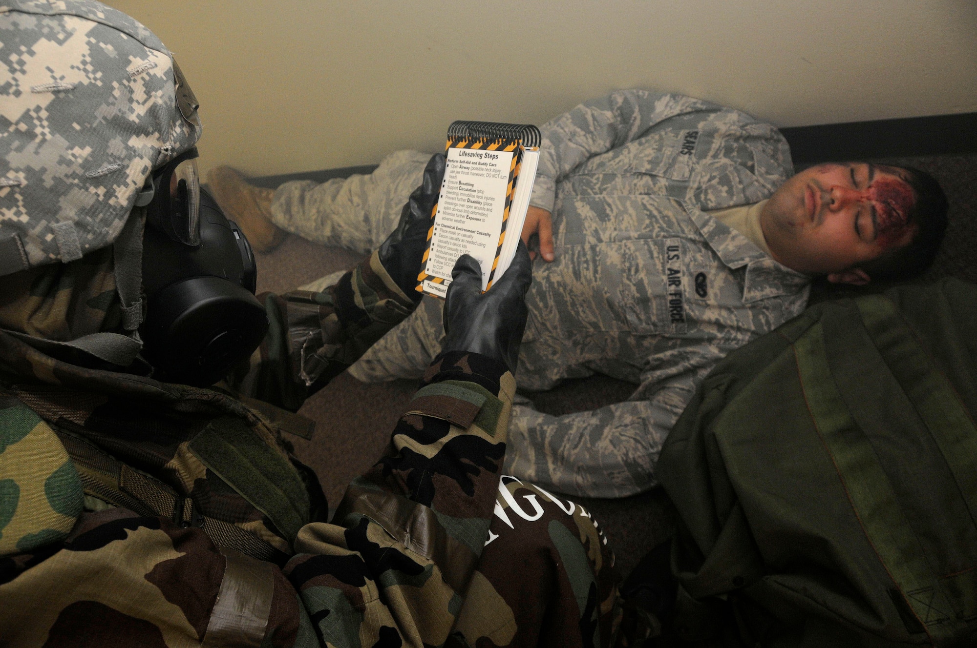 Lt. Col. David Mineau, 18th Operations Support Squadron commander, refers to his Airman's Manual to determine the best method to treat a simulated injury to an Airman during a building evacuation scenario at Kadena Air Base, Jan. 19. This scenario was part of a local operational readiness exercise and tested the 18th OSS’s ability to tend to injured personnel until medical assistance arrives. (U.S. Air Force photo/Staff Sgt. Darnell T. Cannady)