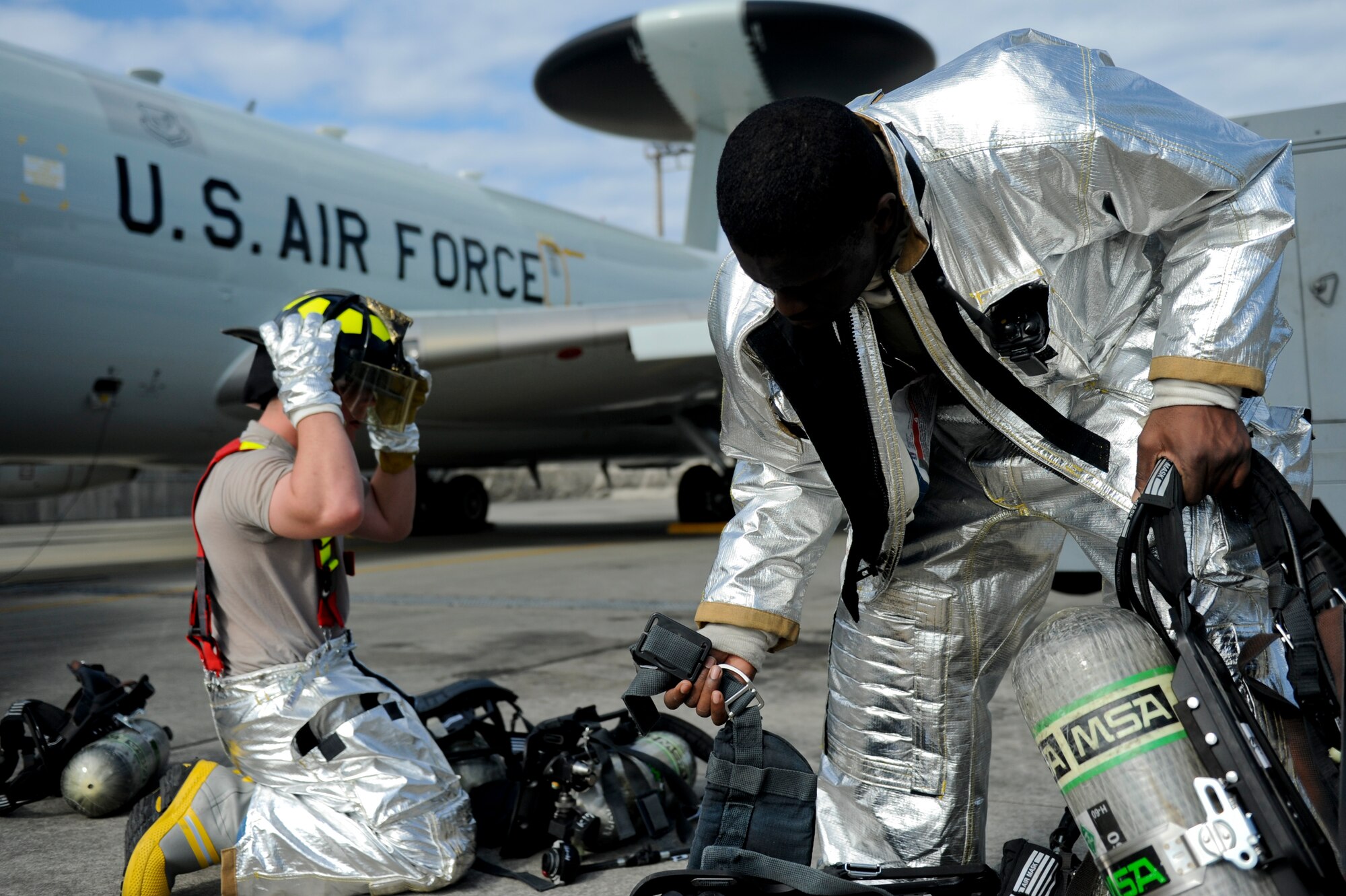 Airman 1st Class Jesse Gresham and Staff Sgt. Phillips Burns, both members of the 18th Civil Engineer Squadron, grab their gear after tending to a simulated E-3 Sentry engine fire Jan. 19. The simulated engine fire was part of Beverly High 11-02, a local operational readiness exercise, and tested the fire department’s ability to respond to an aircraft fire. (U.S. Air Force photo/Staff Sgt. Jonathan Steffen)
