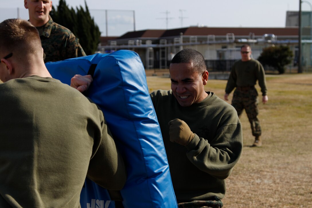 Lance Cpl. Luis Zabala, station Section 3 clerk, viciously pounds his fists into a punching pad during an oleoresin capsicum course at the Provost Marshal’s Office here Jan. 20. While some Marines and sailors found it hard to overcome the burning sensation of the OC spray, others were able use the pain to their advantage.