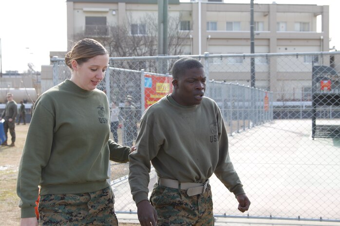 Cpl. Melissa Yocum, a Provost Marshal’s Office training noncommissioned officer, helps lead Pvt. Baaron Knox, a station food service specialist, away to a clearing after completing an oleoresin capsicum course at PMO here Jan. 20. After completing the course, service members were required to walk around in a circle until the burning sensation abated.