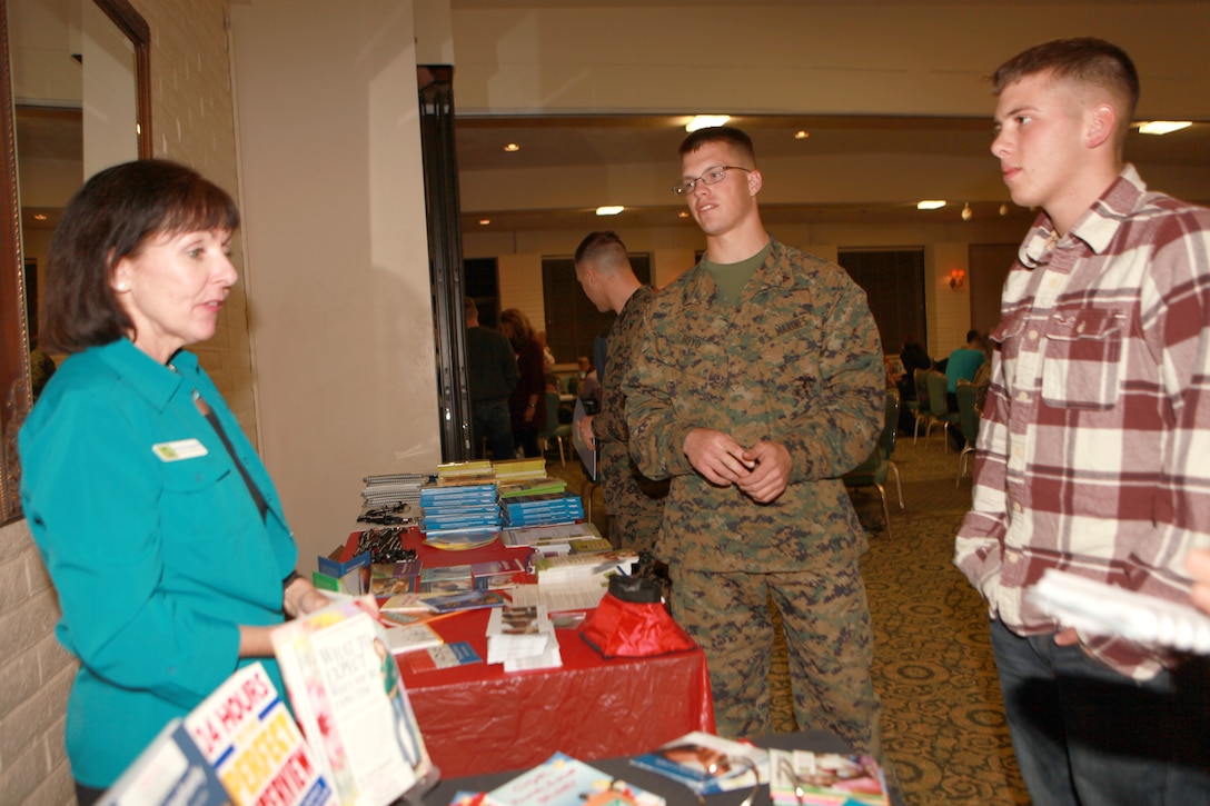 Mary Ann Margosian, an outreach assistant with Military OneSource, explains the resources available to Marines with the 11th Marine Expeditionary Unit during a town hall meeting here Jan 19. Lance Cpl. Zachary J. Boyd, 21, a technical controller with the unit and Pfc. Christian T. Milburn, 18, a data network specialist with the unit, attend one of many informational meetings before the unit's upcoming deployment. The meeting was held to educate service members with the unit and their families about training, communication and resources available to them while their Marine or sailor is deployed.