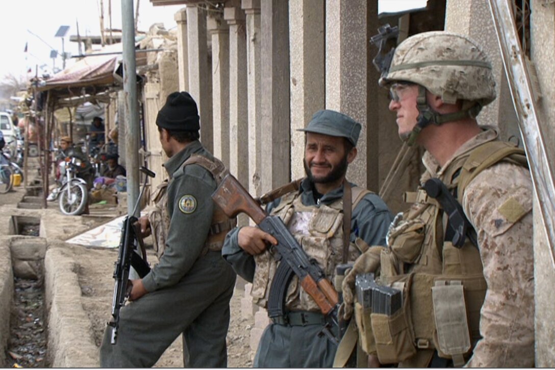Corporal Mason Stevens, a team leader from the police mentor team from 3rd Battalion, 5th Marine Regiment, provides security during a daily patrol in Sangin with members of the Afghan National Police force, Jan. 20.  As time goes on, Marines are allowing the police to take more control of operations in Sangin to help build the confidence of the local people in their government.