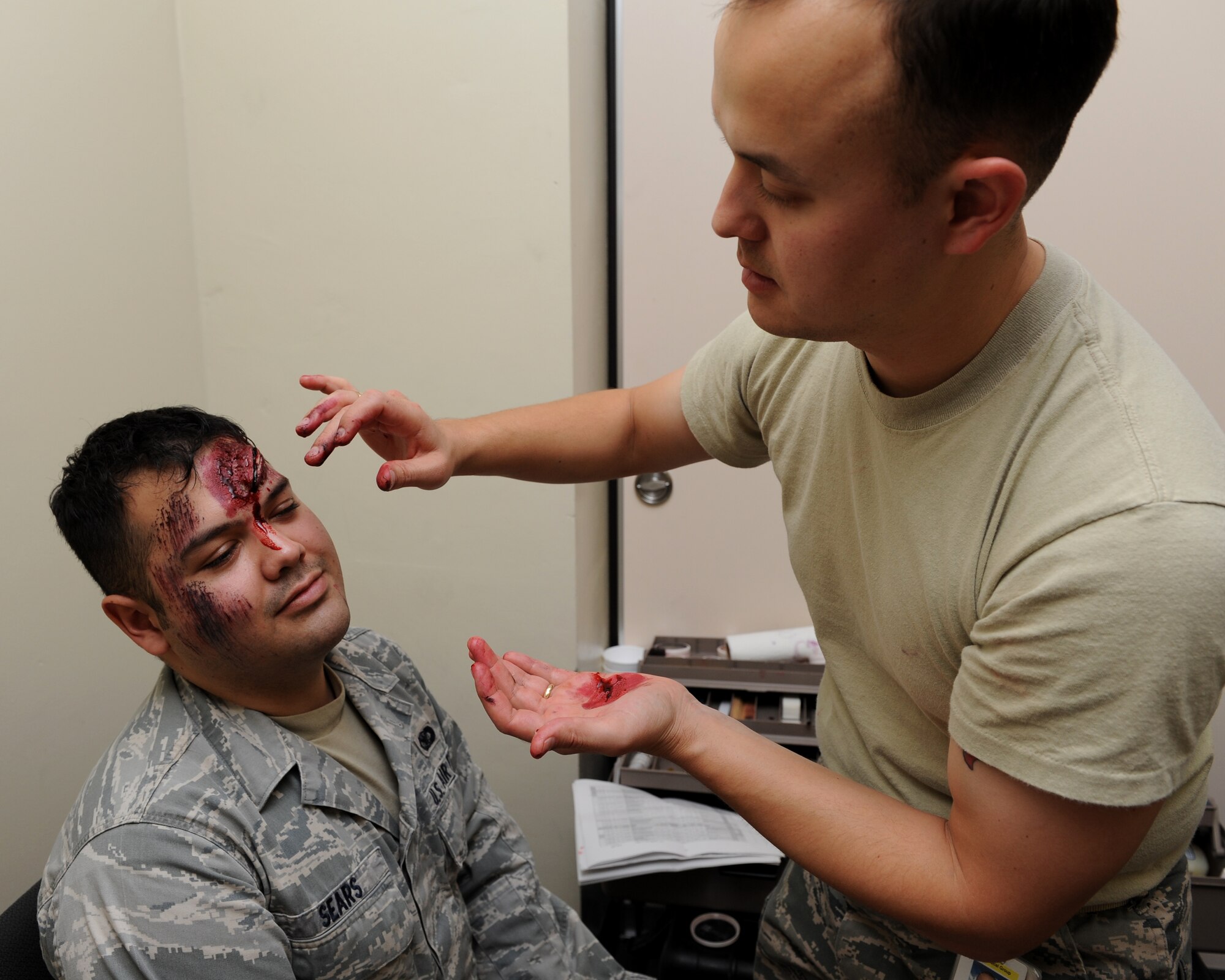 Master Sgt. Nicholaus Stopfer, non-commissioned officer in charge of area dental laboratory from the 18th Dental Squadron, applies a realistic open head wound to Airman Basic Cody Sears, security forces journeyman from the 18th Security Forces Squadron, during a local operational readiness exercise. Volunteer victims, like Airman Sears, provide a more realistic training environment to first responders during emergency scenarios. (U.S. Air Force Photo/ Junko Kinjo)