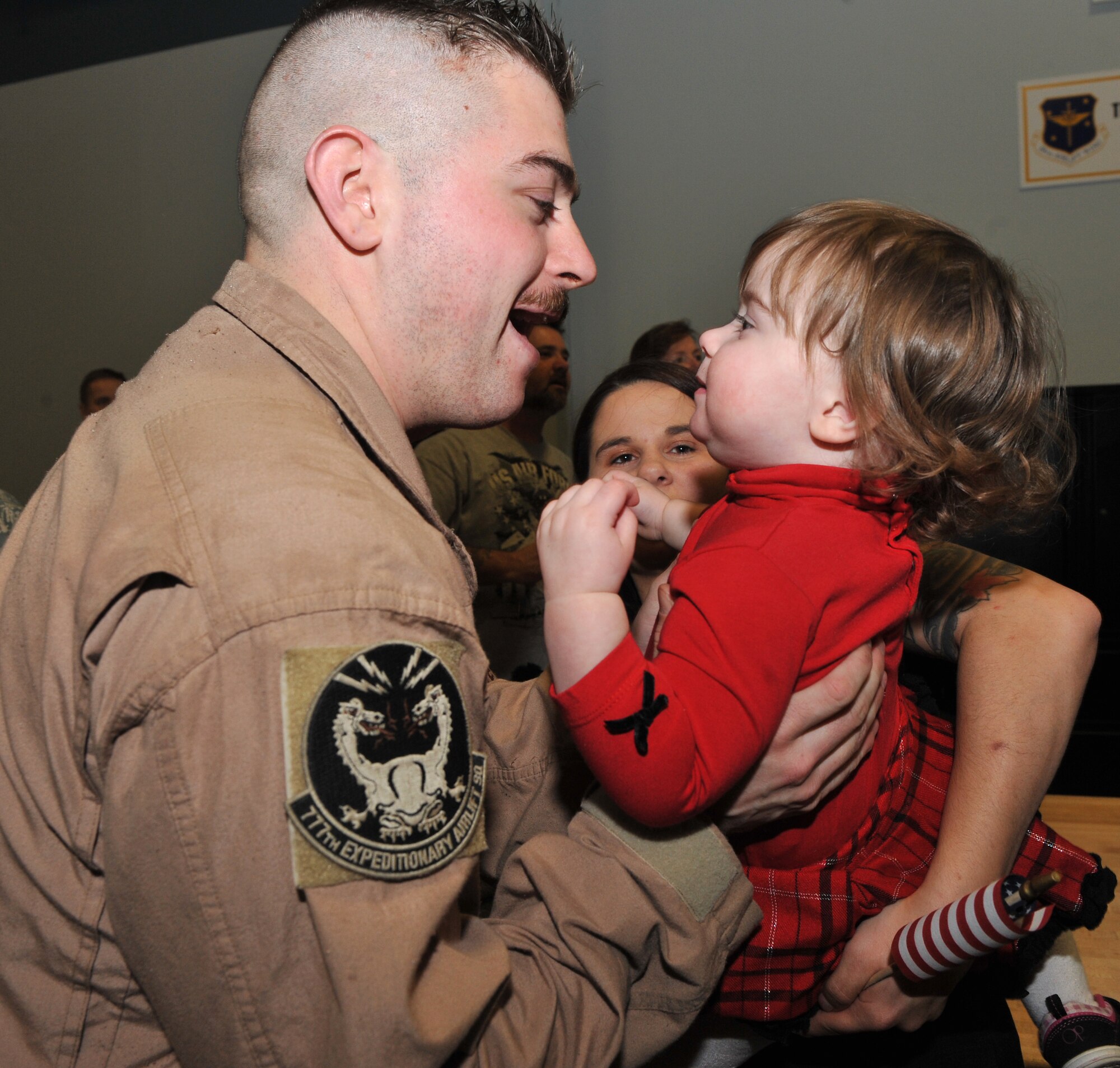 Senior Airman Justin Humber, 50th Airlift Squadron flight engineer, picks up his daughter, Madison; and is greeted by his wife, Donna; after returning home from his deployment Jan. 20, 2011, at Little Rock Air Force Base, Ark.  Airman Humber returned from a five-month deployment in Iraq. (U.S. Air Force photo by Senior Airman Gul Crockett)
