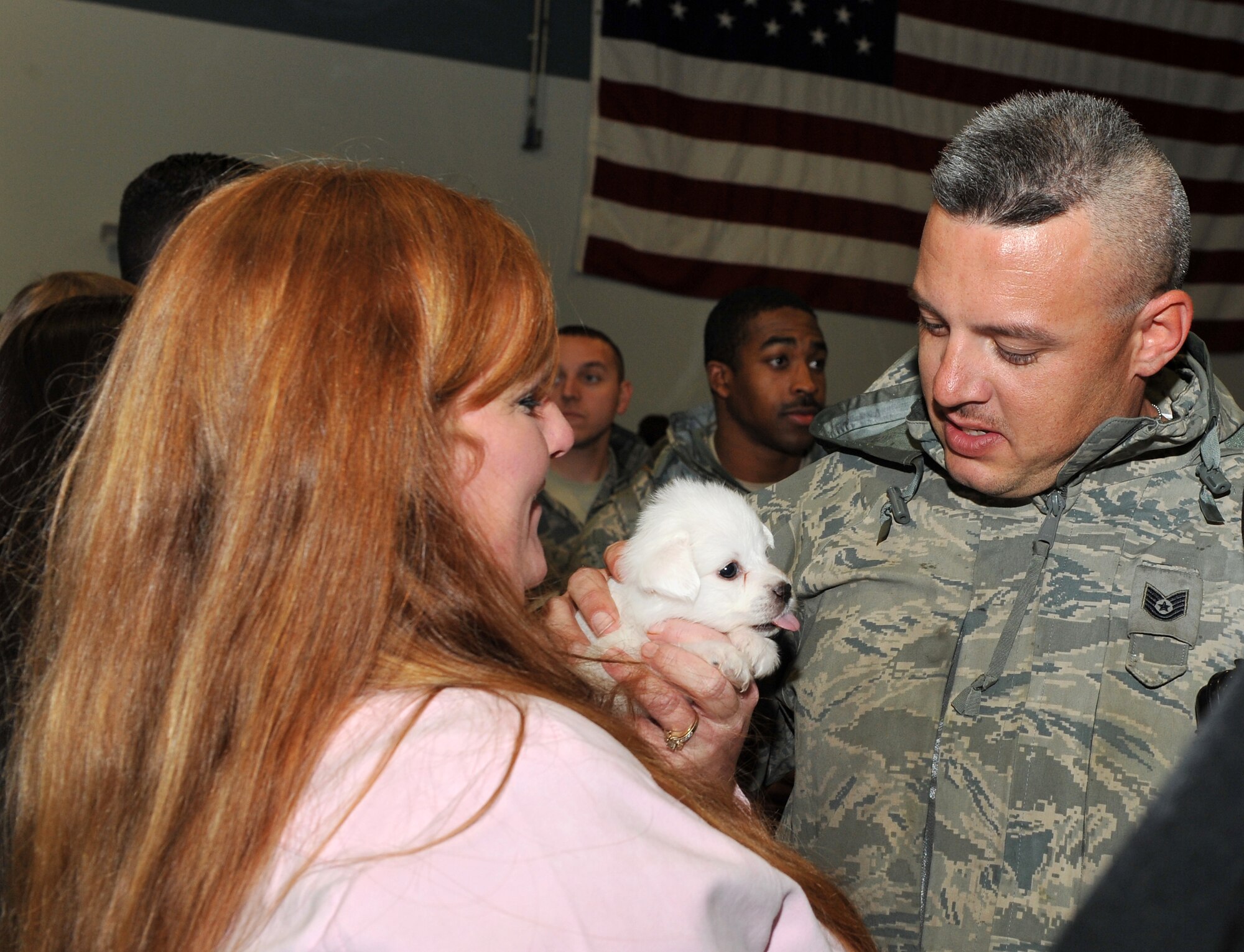 Tech. Sgt. Dwight Carter, 19th Aircraft Maintenance Squadron crew chief, greets his wife, Donna; and their new puppy, Blizzie; Jan. 20, 2011, at Little Rock Air Force Base, Ark. More than 200 Airmen returned from their overseas deployments, being away from their families and friends for up to six months. (U.S. Air Force photo by Senior Airman Gul Crockett)