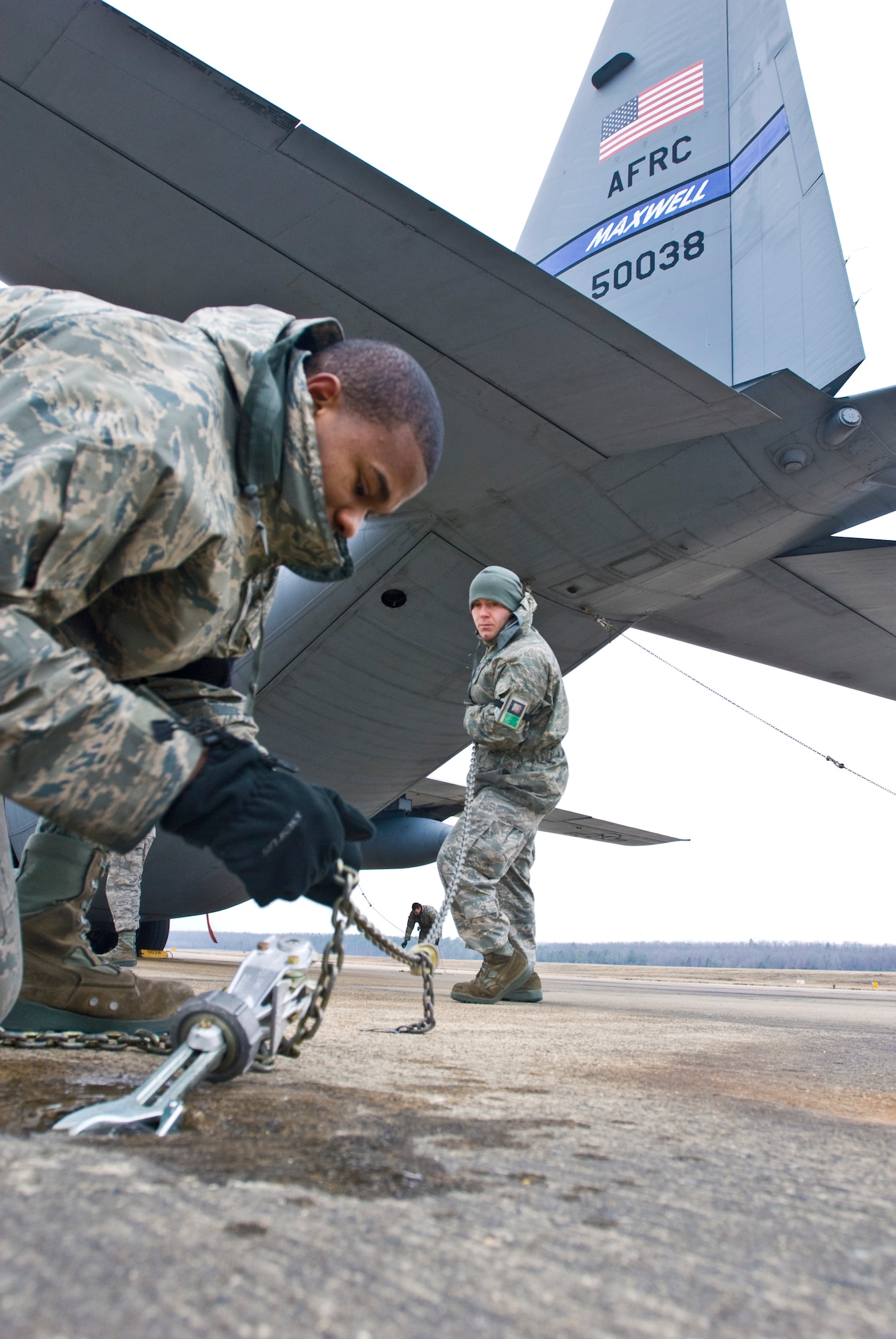 Airman 1st Class Tyler Butler (left) and Staff Sgt. Jordan Smith, both crew chiefs with the 314th Aircraft Maintenance Squadron, chains down a C-130 Hercules Jan. 19, 2011, at Little Rock Air Force Base, Ark. The purpose of chaining, or mooring, an airplane is to secure it during inclement weather. (U.S. Air Force photo by Staff Sgt. Nestor Cruz)