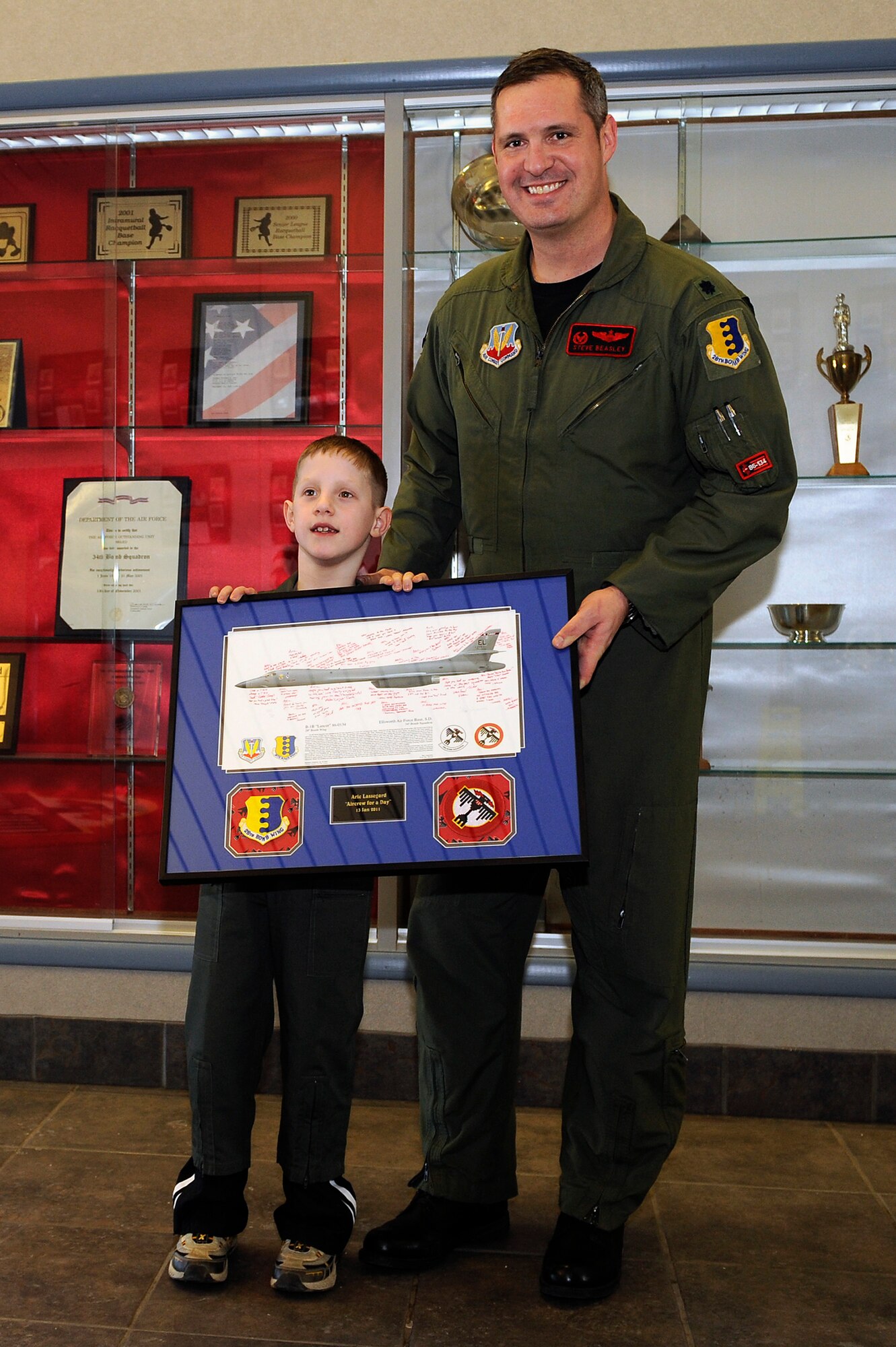 Lt. Col. Steven Beasley, 34th Bomb Squadron commander, presents Aric Lassegard with a signed lithograph at Ellsworth Air Force Base, S.D., Jan. 13, 2011.  Aric was treated as an honorary member of the 34th BS for the day as part of the Aircrew for a Day program.  Because of this, he was given the same memento given to all aircrew members when they leave the squadron. (U.S. Air Force photo/Staff Sgt. Marc I. Lane)