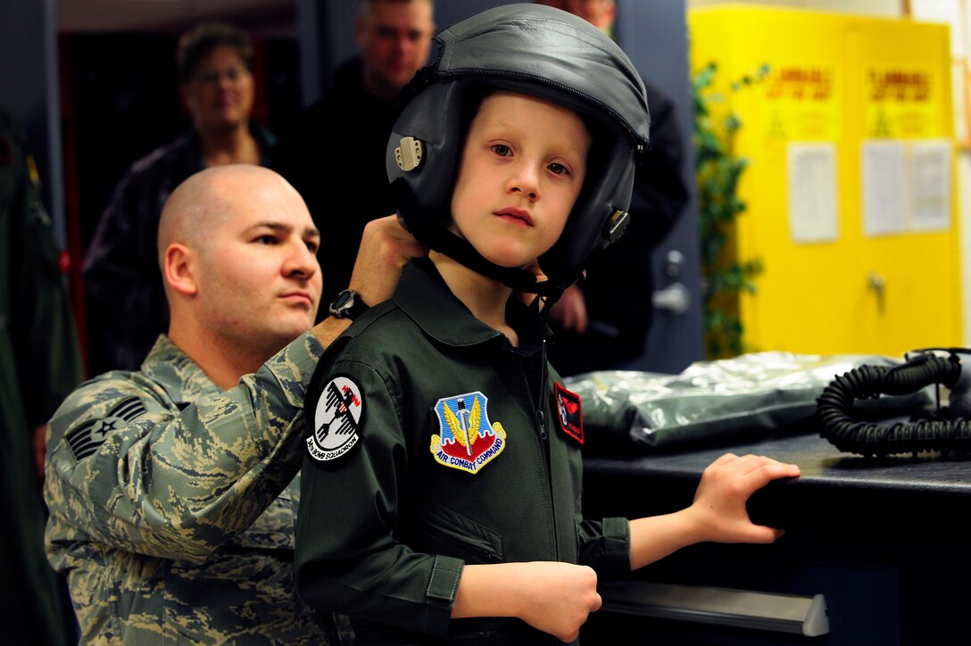 Tech. Sgt. Chris Shapiro, 34th Bomb Squadron aircrew flight equipment assistant NCO in charge, assists Aric Lassegard, 34th BS honorary aircrew,  as he puts on an HGU-55/P aircrew helmet at Ellsworth Air Force Base, S.D., Jan. 13, 2011.  The 34th BS gave Aric his own flight suit with name tag and unit patches as well as a flyer’s helmet with mask as part of the Aircrew for a Day program.  (U.S. Air Force photo/Staff Sgt. Marc I. Lane)