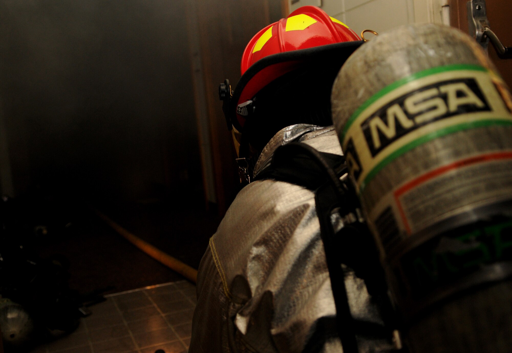 A fireman from the 18th Civil Engineer Squadron enters a simulated burning building to extract potentially injured personnel during Beverly High11-02, a local operational readiness exercise at Kadena Air Base, Japan, Jan. 20. The scenario tested the skills and capabilities of Kadena's emergency response personnel. (U.S. Air Force photo/Airman 1st Class Jarvie Z. Wallace)
