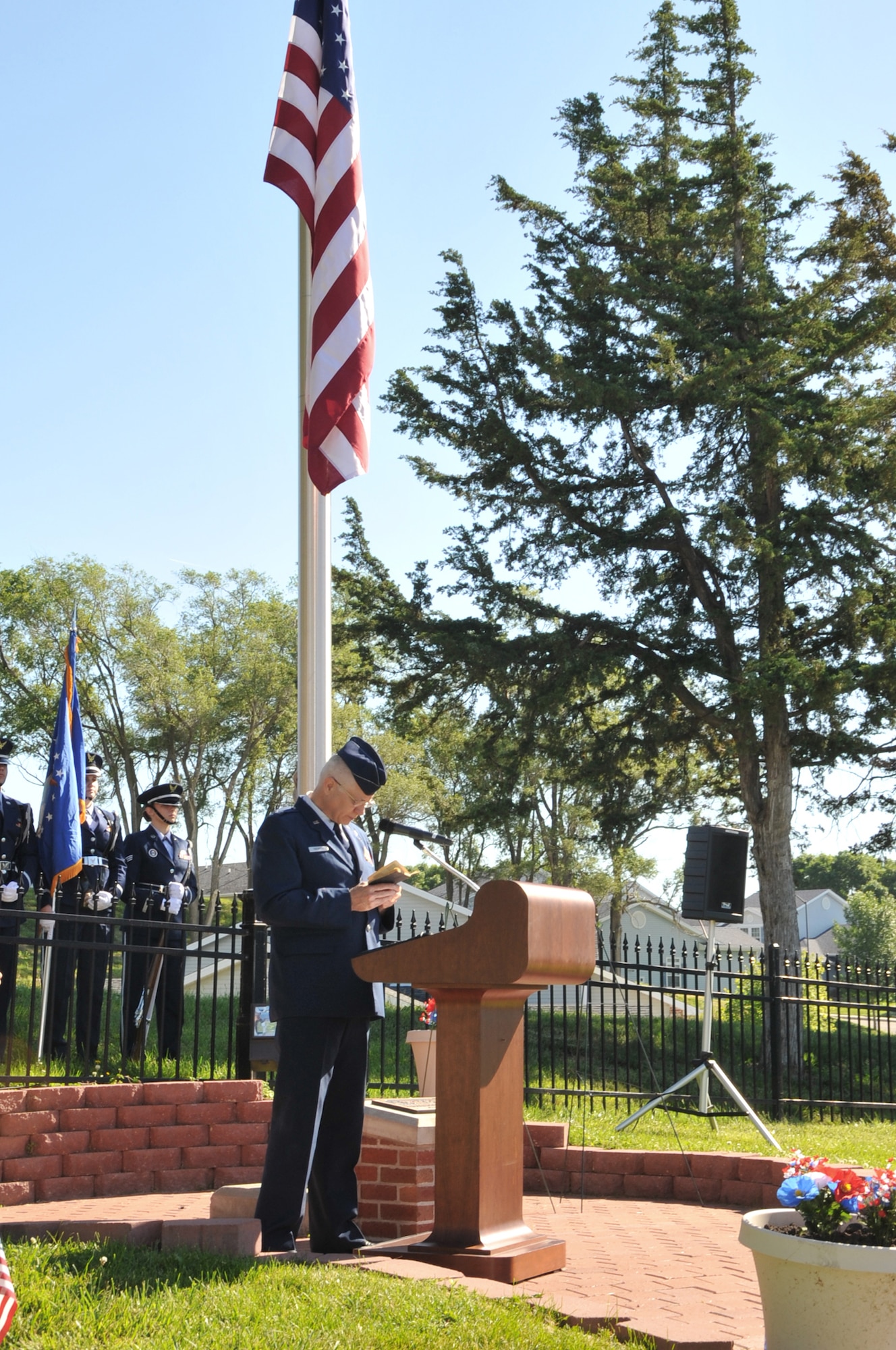 Underneath the U.S. flag Chaplain (Col.) Carl Swanson reads a prayer to honor all service members who made the ultimate sacrifice while serving their country during a Memorial Day ceremony at the base cemetery May 31, 2010, at Offutt Air Force Base, Neb. Chaplain Swanson is the 55th Wing chief chaplain. (U.S. Air Force photo/D.P. Heard)