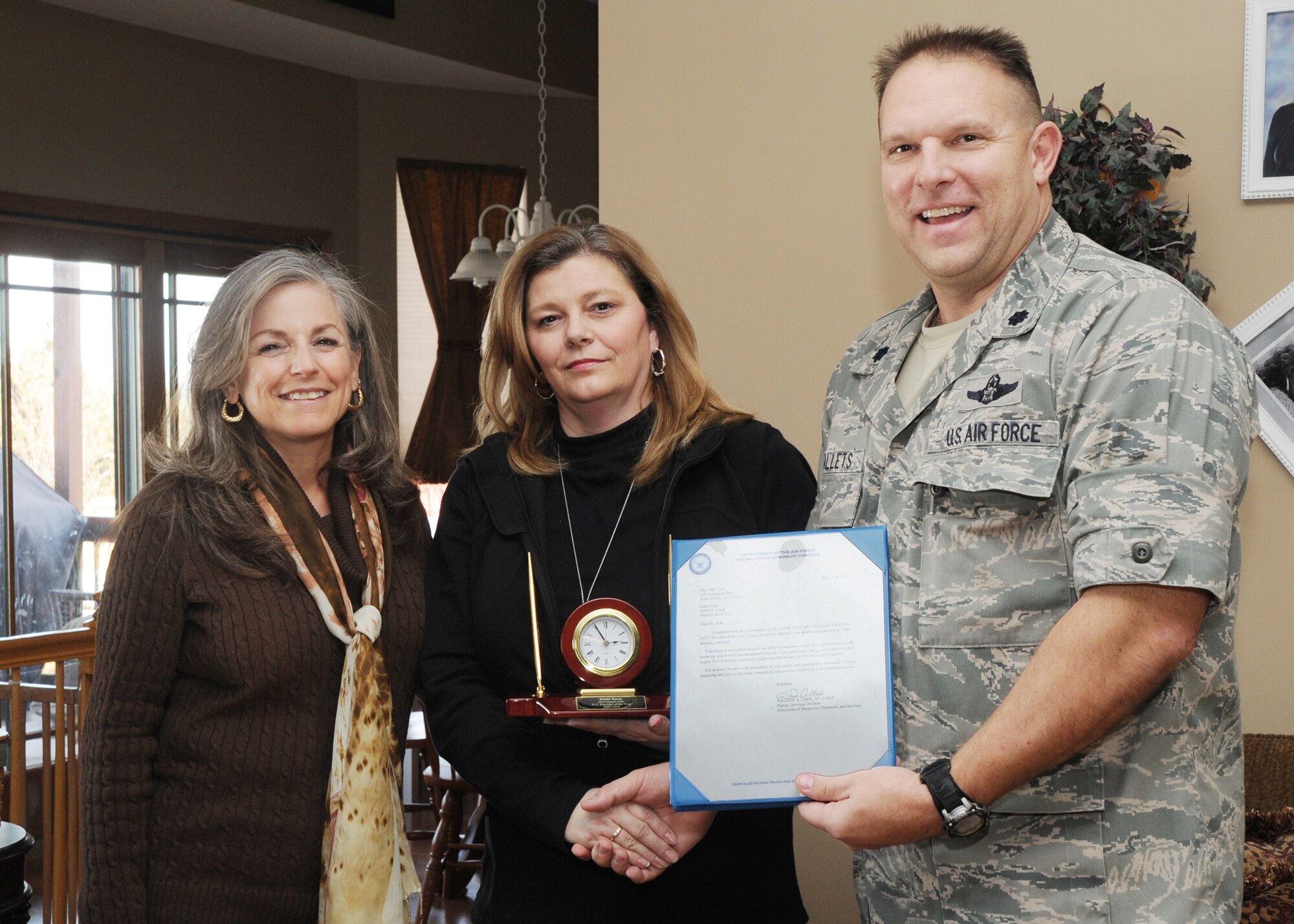 Diana Johns, wife of Gen. Raymond E. Johns, Jr., Air Mobility Command commander, and Lt. Col. Robert Mallets, 22nd Mission Support Group deputy commander, presents Eddie Portz, McConnell child care provider, with the Air Mobility Command Family Child Care Provider of the Year Award Jan. 13, 2011, Wichita, Kan. Mrs. Portz renovated her home to accommodate the children she cares for. (U.S. Air Force Photo/Airman 1st Class Katrina M. Brisbin)