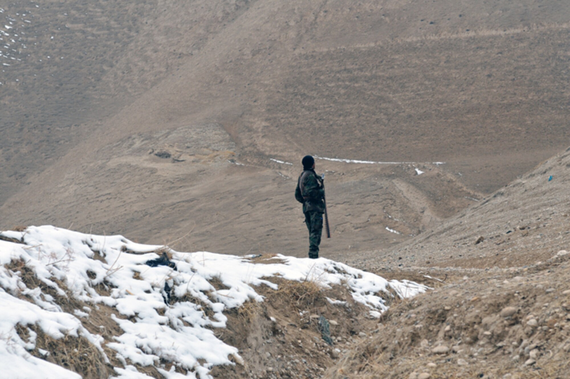 BADGHIS, Afghanistan -- An Afghan National Army soldier stands guard and looks up to a mountain ridgeline, in Nawbor Village, Bala Murghab District, Badghis Province, Afghanistan, Jan. 16, 2011. ANA teamed up with White Platoon U.S. Army scouts, Bulldog Troop, who hail from 7th Squadron, 10th Cavalry Regiment, 1st Brigade, 4th Infantry Division, at Fort Carson, Colo., during the patrol. (U.S. Air Force photo/Tech. Sgt. Kevin Wallace)