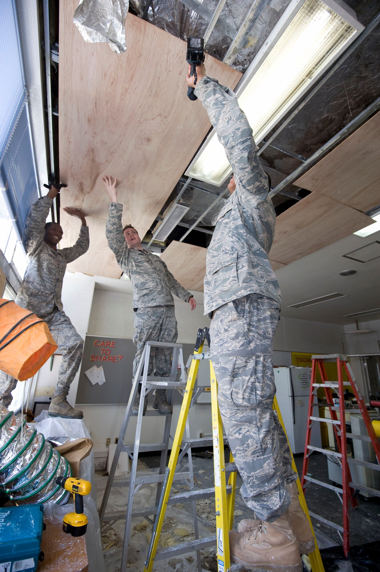 U.S. Air Force Airmen from the 35th Civil Engineer Squadron structure shop, secure plywood to the ceiling of Cummings Elementary School, Misawa Air Base, Japan, Jan. 18, 2011. Plywood is used to minimize the cold air from coming into the room. (U.S. Air Force photo by Tech. Sgt. Russell McBride/Released)