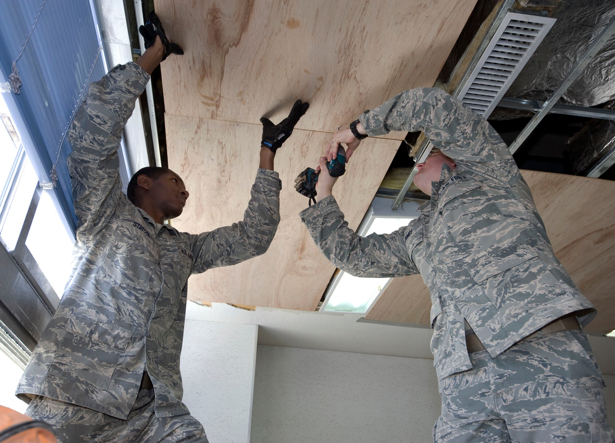 U.S. Air Force Senior Airman Ricky Gennie, 35 Civil Engineer Squadron structural journeyman, and Airman 1st Class Jesse James, structural apprentice, secure plywood to the ceiling of Cummings Elementary School at Misawa Air Base, Japan, Jan. 18, 2011. During the previous weekend the school had water damage causing a two-day delay for children returning to school. (U.S. Air Force photo by Tech. Sgt. Russell McBride/Released)