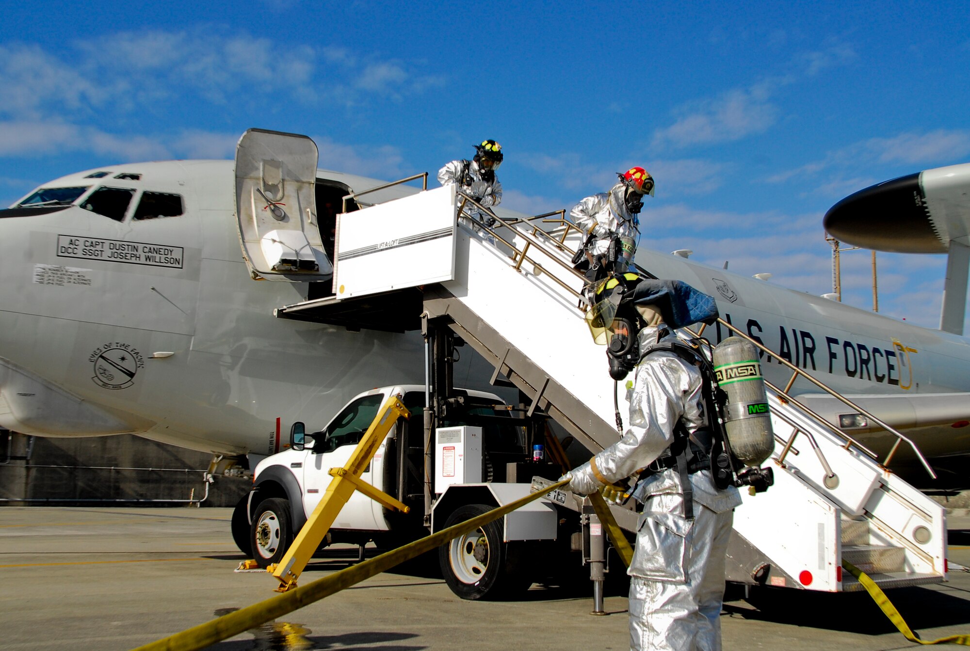 Firemen from Kadena's 18th Civil Engineer Squadron drag a fire hose into a simulated burning aircraft during Beverly High 11-02, a local operational readiness exercise on Kadena Air Base, Japan, Jan. 19. Kadena's firemen, security forces, and flight medicine personnel worked together during the simulation to save the lives of the acting victims aboard the aircraft. (Air Force photo/ Airman 1st Class Maeson L. Elleman)
