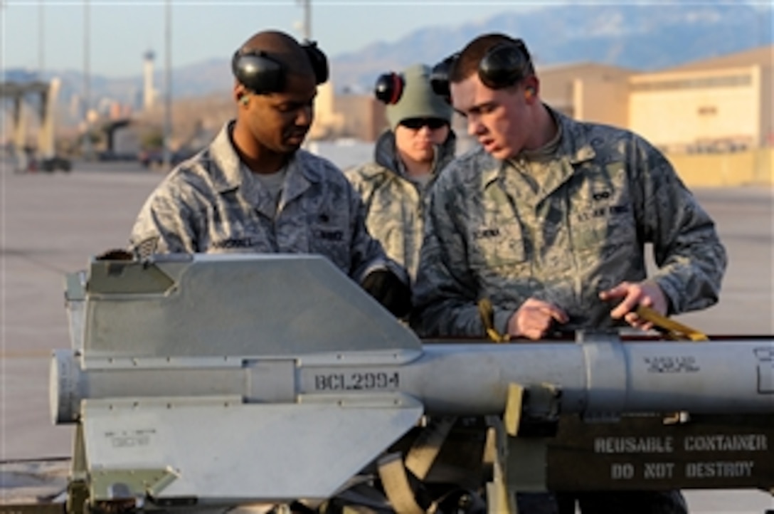 U.S. Air Force Airman 1st Class Michael Schena (right) and Staff Sgt. Melvin Marshall (left), both 757th Aircraft Maintenance Squadron aircraft armament systems specialists, prepare an AIM-9M Sidewinder heat-seeking air-to-air missile for loading onto an F-15 Eagle aircraft during a weapons load competition on the flight line at Nellis Air Force Base, Nev., on Jan. 14, 2011.  Weapons load teams are evaluated for use of the checklist, safety and overall speed during the quarterly competitions.  