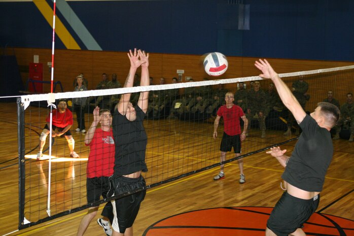 Michael Salinas (left), Combat Logistics Company 36 volleyball player, throws up both hands while leaping in anticipation of Matthew Lowry’s, Marine Aviation Logistics Squadron 12 volleyball player, spike during the Commander’s Cup Volleyball Single Elimination Challenge at the IronWorks Gym sports courts here Jan. 21. Salinas proved critical to CLC-36’s comeback against MALS-12 in the championship match.