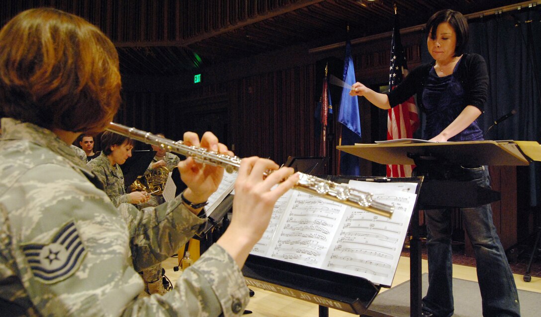 Chie Imaizumi, right, conducts during a rehearsal of her musical piece, "Opening New Doors," while Tech. Sgt. Julia Taylor, left, plays flute. "Opening New Doors" is the first piece Ms. Imaizumi, a native of Saitama, Japan, has composed for an orchestral band. Sergeant Taylor, a native of Telford, Penn., performs for the Air Force Academy Band's marching and concert bands and Academy Winds ensemble. (U.S. Air Force photo/Staff Sgt. Don Branum)