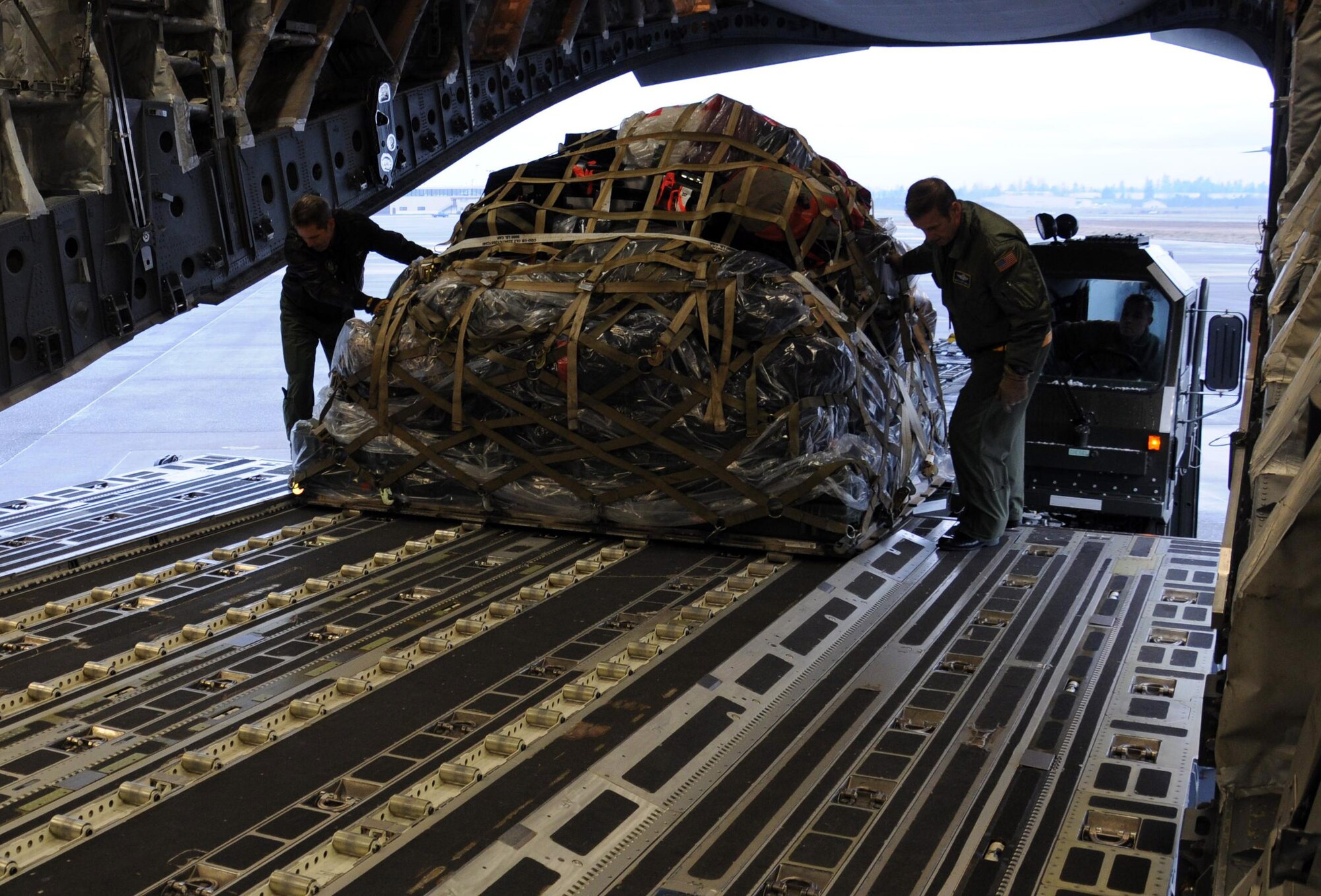 MCCHORD FIELD, Wash.- Chief Master Sgt. Jim Masura (left), 446th Operations Group standard evaluation loadmaster and Chief Master Sgt. Ron Campeau, 313th Airlift Squadron resource manager loadmaster, prepare to secure a luggage pallet on a C-17 Globemaster III before leaving for a training mission to Joint Base Pearl Harbor-Hickam, Jan. 10. Chief Campeau's training was a loadmaster evaluaion by Chief Masura. Loadmasters need this training every 17 months in order to keep their qualifications current, so they can be ready to deploy and support the global airlift mission. (U.S. Air Force photo/Master Sgt. Jake Chappelle)