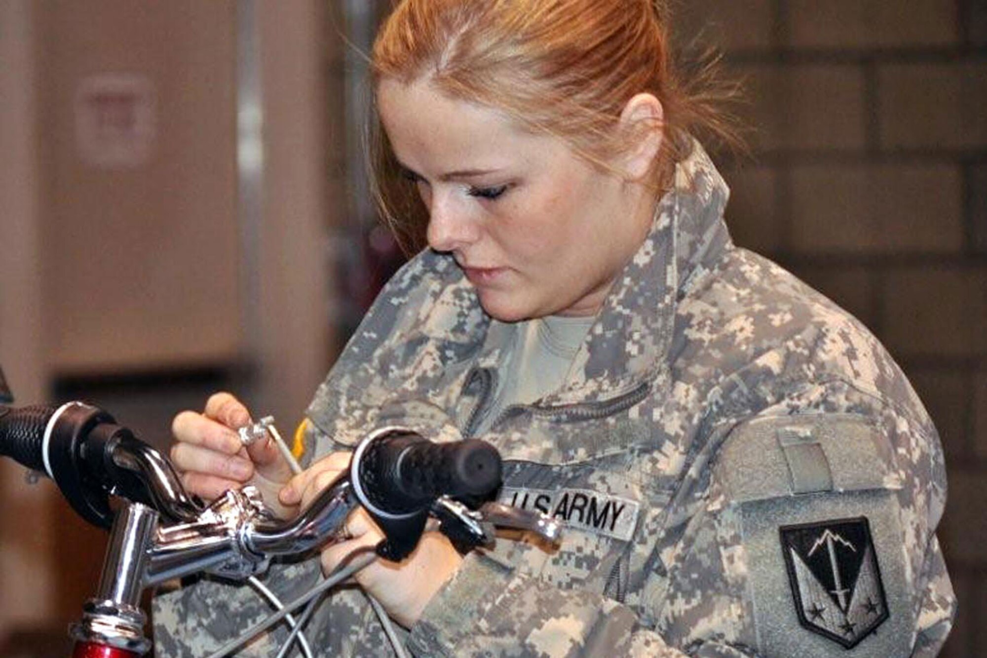Spc. Rachel Skalisky, 793rd Military Police Battalion, takes her time to ensure that she correctly puts together the brakes on her recipients bicycle Monday at the Spenard Recreation Center, Anchorage. (U.S. Army photo/Sgt. Tamika Dillard)
