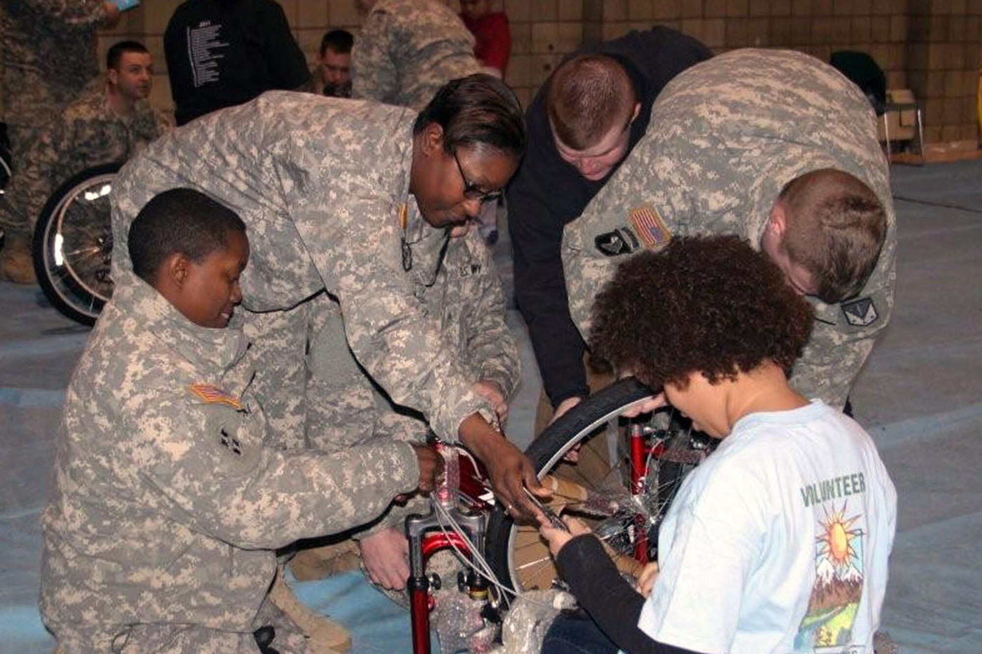 Sgt. Camilia Hall, Sgt. Alikeisha Bryant, Pfc. Stephen Tronell, Spc. Ryan Hatfield and Natasha Coates, 10, unwrap a bike. (U.S. Army photo/Sgt. Tamika Dillard)