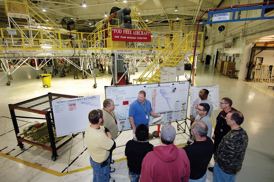 Mike Bassham, a sheet metal supervisor in the 565th Aircraft Maintenance Squadron’s B-52 Production Flight, talks to his team of mechanics gathered around a script board by a B-52 in Bldg. 2121. A transformation tool that shows every worker and supervisor the production status of the aircraft to a fine detail, past scripts can help identify areas for improvements or successes. The boards easily show everyone their part of the production work and identify what still needs to be done. “If there’s not a roadmap of where we’re going, then everybody is going in different directions,” said Mr. Bassham. (Air Force photo by Margo Wright)