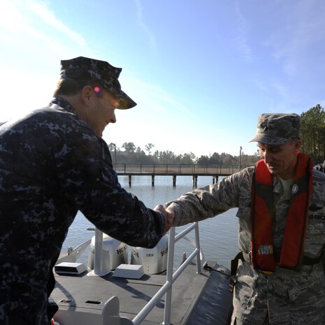 Navy Chief Warrant Officer 3 John WIlson welcomes Brig. Gen. William Bender, commander, United States Air Force Expeditionary Center, onboard a patrol boat at Joint Base Charleston - Weapons Station, Jan. 20. General Bender visited JB CHS for the first time after the realignment of the 628th Air Base Wing under the U.S. Air Force Expeditionary Center.