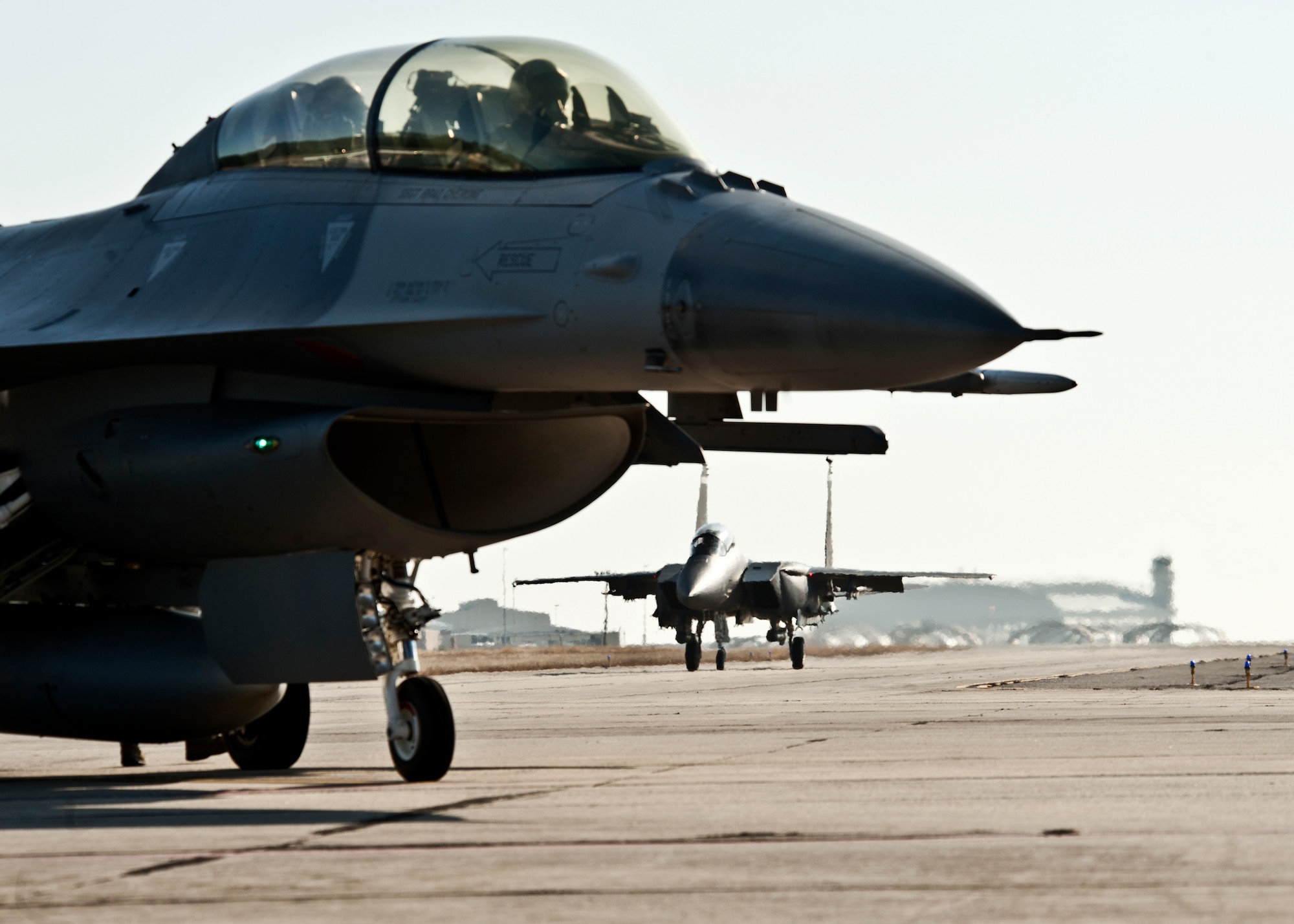 An F-16 waits for clearance as an F-15E Strike Eagle taxis in the distance at Eglin Air Force Base Fla., Jan. 18.  Both aircraft belong to the 46th Test Wing.  (U.S. Air Force photo/Samuel King Jr.)