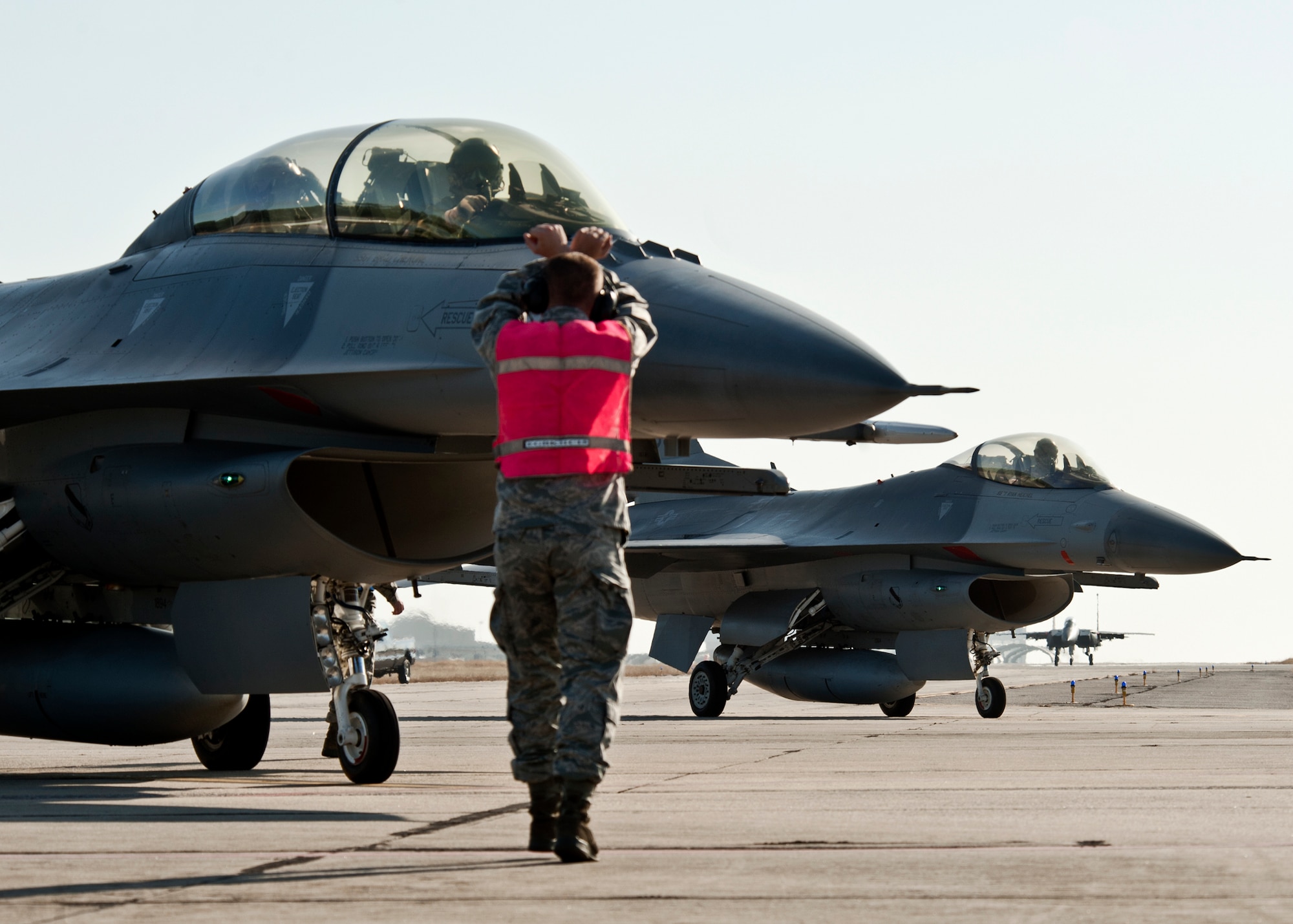 A maintainer from the 46th Maintenance Group halts one F-16 as another rolls by and an F-15E taxis in the distance at Eglin Air Force Base Fla., Jan. 18.  (U.S. Air Force photo/Samuel King Jr.)