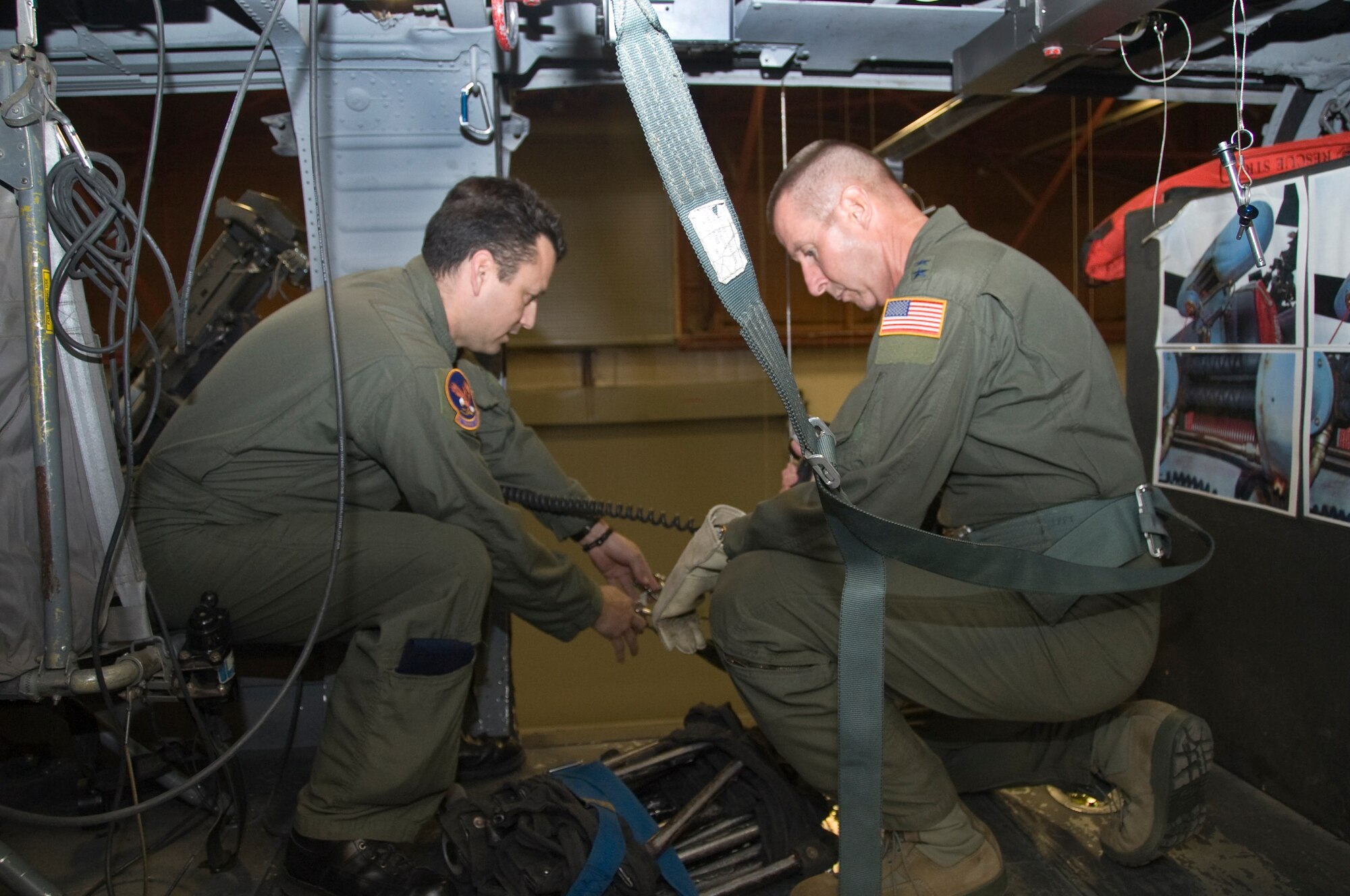 Tech. Sgt. Josemaria Gonzalez, 58th Training Squadron, left, assists Maj. Gen. Mark Solo with a safety harness in the Monster Garage.  .  U.S. Air Force Photo by Elizabeth Martinez.