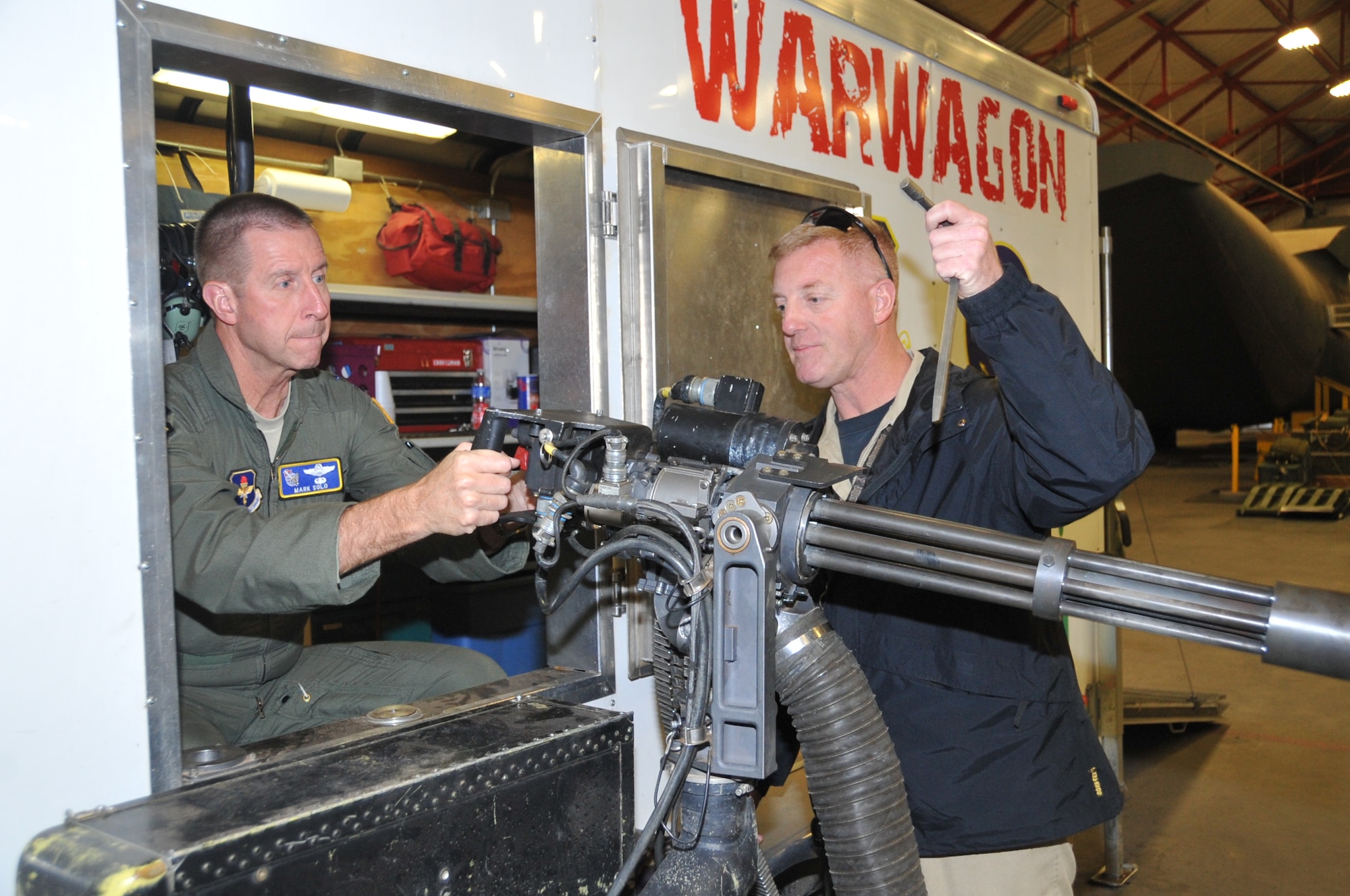 James Sargent, 58th Training Squadron, right, removes the safety on a training gun hitched to the Warwagon for Maj. Gen. Mark Solo.  U.S. Air Force Photo by Elizabeth Martinez.