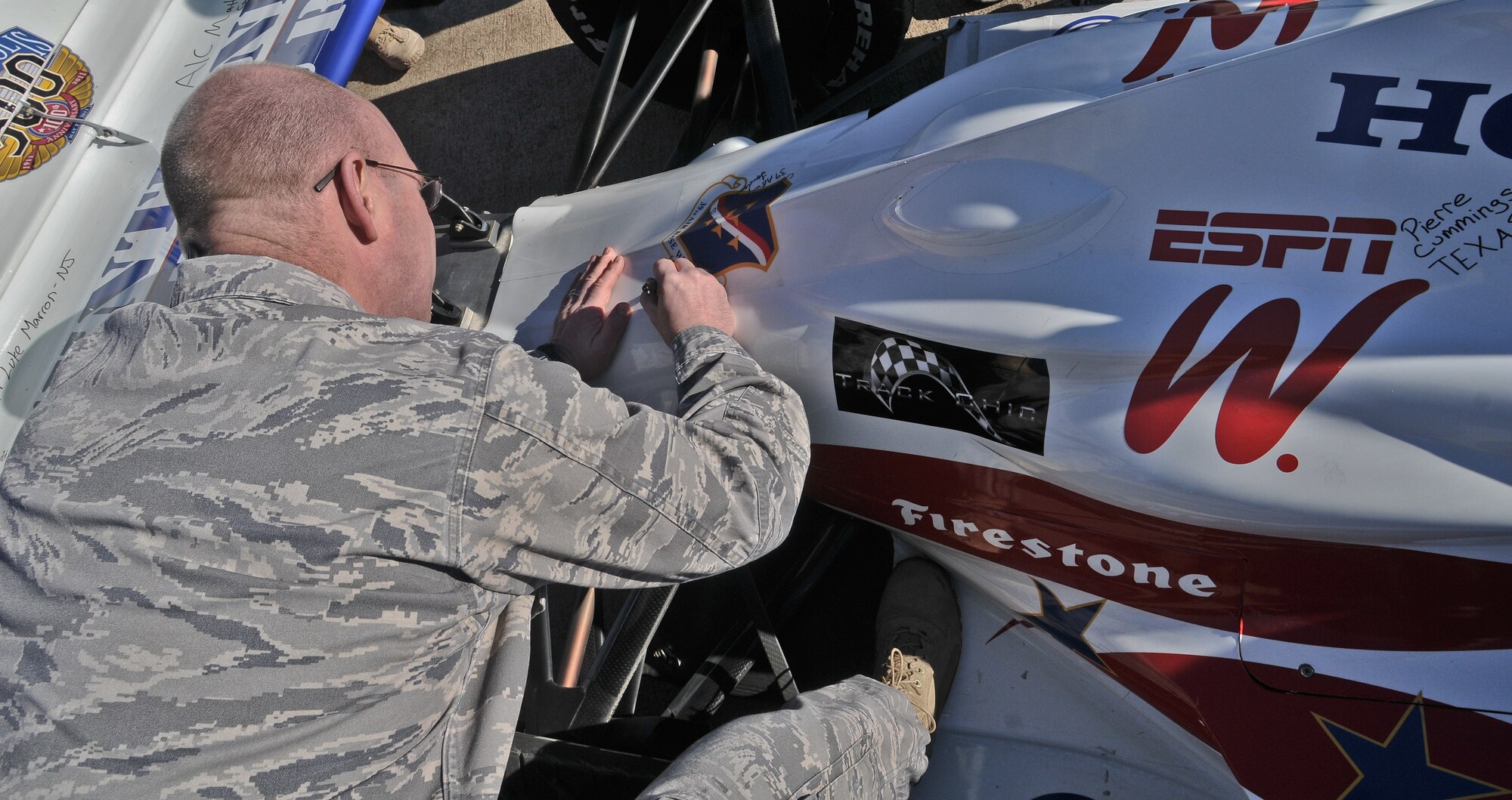 Col. Scott Enold, 39th Mission Support Group commander, adds a 39th Air Base Wing sticker and his signature to the Indy 500 Centennial Tour race car Jan. 19, at Incirlik Air Base, Turkey. During the Indianapolis 500 Tour, Airmen were allowed to sign their names and hometown to the demo car that will be displayed in museums.  The Indy 500 Centennial Tour, coordinated by Morale Entertainment Foundation and Armed Forces Entertainment, in conjunction with the IZOD Indy Car Series and the Indianapolis Motor Speedway, is a 10-day morale trip to Europe and the Middle East with the goal of boosting the morale of more than 10,000 servicemembers. The team, which includes Indianapolis 500 winners Mario Andretti, Johnny Rutherford and Al Unser Jr. plus Indy 500 veterans Sarah Fisher, Davey Hamilton, Larry Foyt and Firestone Indy Lights race winner Martin Plowman, spoke with the winners and signed autographs during the visit. (U.S. Air Force photo by Staff Sergeant Alexandre Montes/Released)