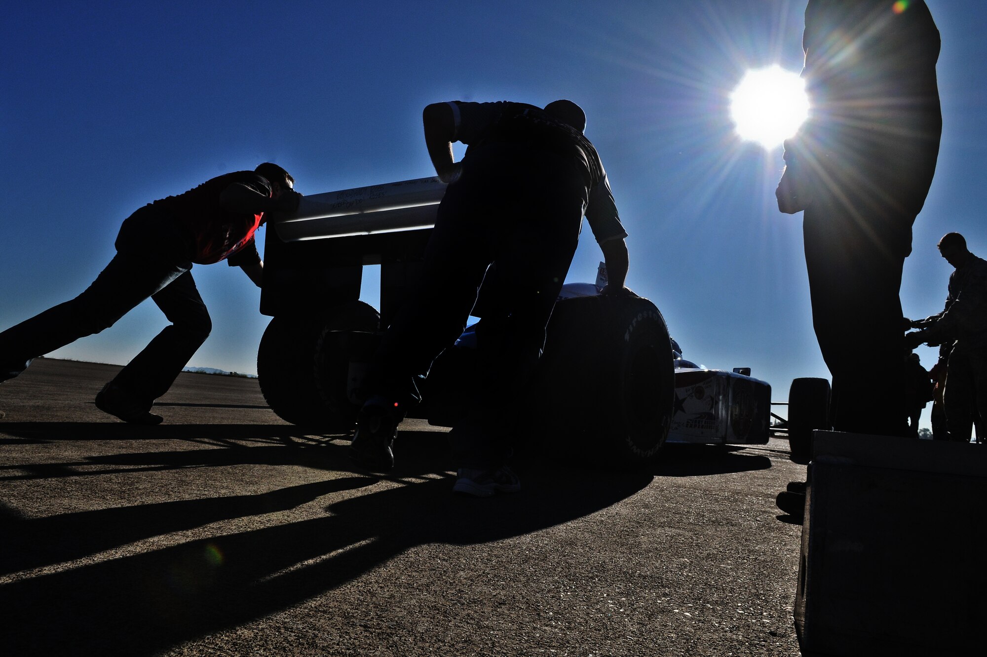 Crew members on the Indianapolis 500 Centennial Tour team push start the car carrying Indy 500 legend Mario Andretti and a demo ride winner Jan. 19, at Incirlik Air Base, Turkey. More than 30 individuals were chosen to ride in the Indy 500 racecar. The Indy 500 Centennial Tour, coordinated by Morale Entertainment Foundation and Armed Forces Entertainment, in conjunction with the IZOD Indy Car Series and the Indianapolis Motor Speedway, is a 10-day morale trip to Europe and the Middle East with the goal of boosting the morale of more than 10,000 servicemembers. The team, which includes Indianapolis 500 winners Mario Andretti, Johnny Rutherford and Al Unser Jr. plus Indy 500 veterans Sarah Fisher, Davey Hamilton, Larry Foyt and Firestone Indy Lights race winner Martin Plowman, spoke with the winners and signed autographs during the visit. (U.S. Air Force photo by Staff Sergeant Alexandre Montes/Released)