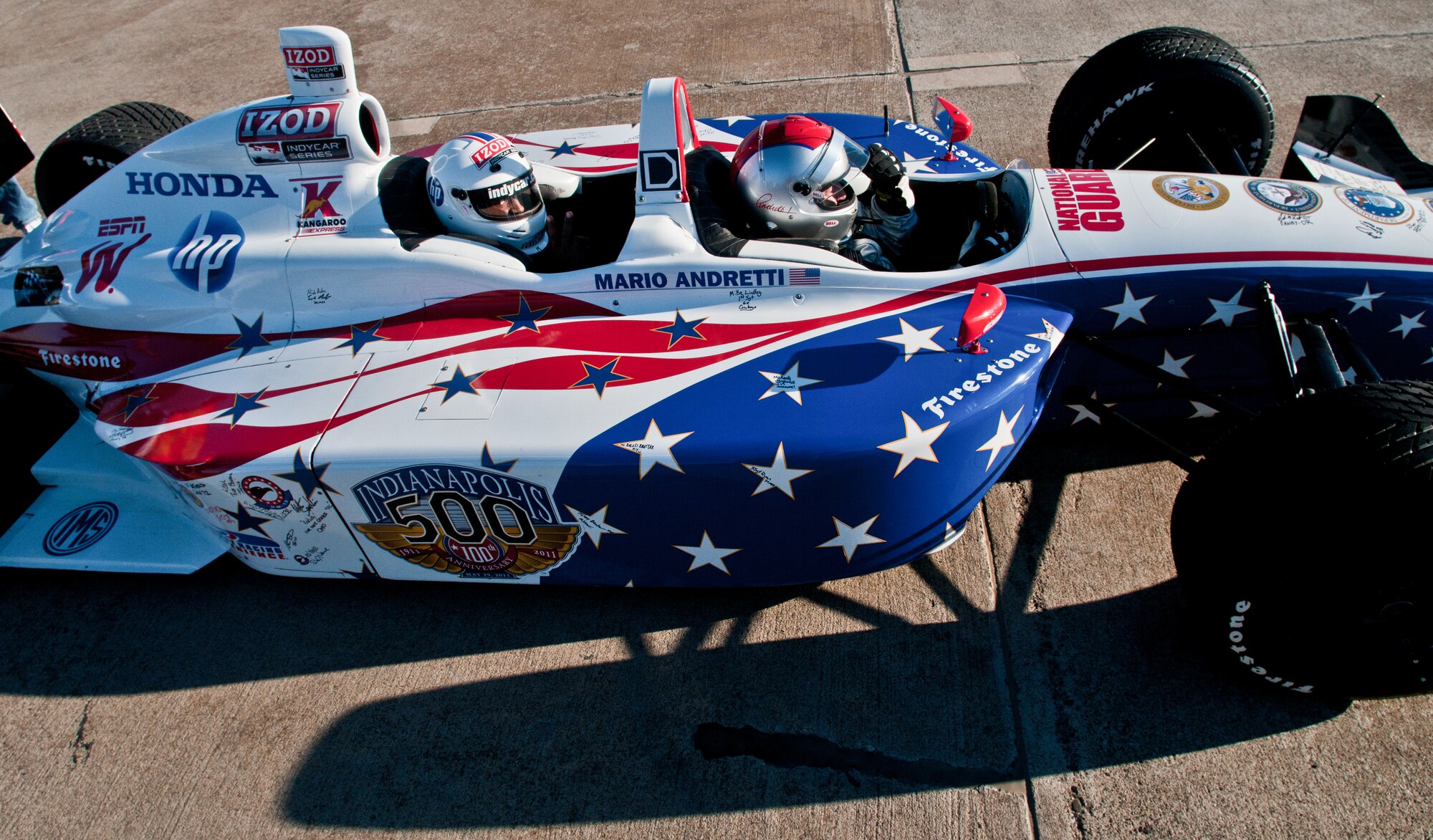 Airman 1st Class Pierre Cummings from the 39th Maintenance Squadron, sits behind Mario Andretti, legendary four-time Indianapolis 500 race winner, for a demo ride during the Indy 500 Centennial Tour Jan. 19, at Incirlik Air Base, Turkey. More than 30 individuals were chosen to ride in the Indy 500 racecar. The majority of the winners were from a drawing throughout the base, and the rest were chosen by their first sergeants. The Indy 500 Centennial Tour, coordinated by Morale Entertainment Foundation and Armed Forces Entertainment, in conjunction with the IZOD Indy Car Series and the Indianapolis Motor Speedway, is a 10-day morale trip to Europe and the Middle East with the goal of boosting the morale of more than 10,000 servicemembers. The team, which includes Indianapolis 500 winners Mario Andretti, Johnny Rutherford and Al Unser Jr. plus Indy 500 veterans Sarah Fisher, Davey Hamilton, Larry Foyt and Firestone Indy Lights race winner Martin Plowman, spoke with the winners and signed autographs during the visit. (U.S. Air Force photo by Staff Sergeant Alexandre Montes/Released)