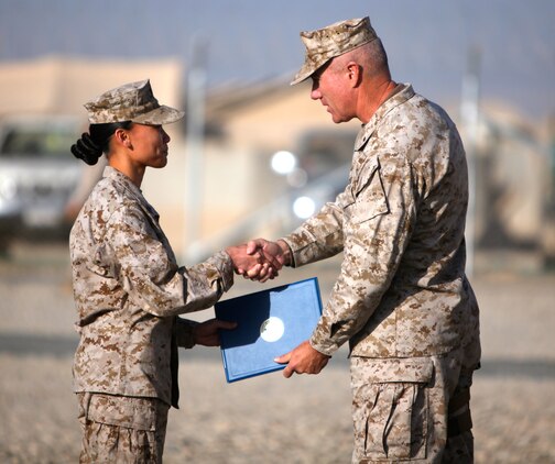 Petty Officer 1st Class Chat Rice, leading petty officer of patient tracker, Health Service Support Element, G-3, 1st Marine Logistics Group (Forward), shakes hands with Brig. Gen. Charles L. Hudson, commanding general of 1st MLG (FWD), during her re-enlistment ceremony on Camp Leatherneck, Afghanistan, Jan. 21. Rice, a native of San Diego, committed to an additional six years of active duty service in the Navy. Rice is currently deployed in the same unit with her husband of nearly eight years, Marine Staff Sgt. Jeff Rice.