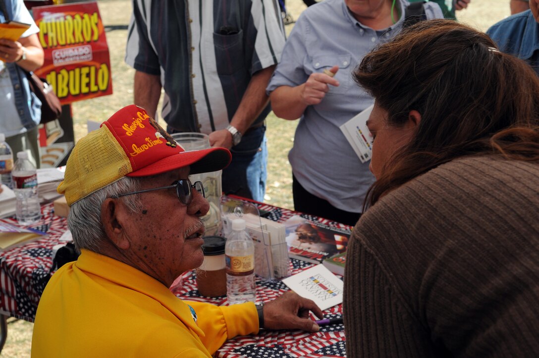 Bill Toledo, a former Marine and Navajo Code Talker in World War II's Pacific island hopping campaign, speaks with a visitor at the Yuma Quartermaster Depot Jan. 22, 2011, during the first Spirit of Yuma Military Festival. Toledo, who fought in the famed battles of both Guam and Iwo Jima, spoke to attendees about his experiences in the war and memories of the Corps.
