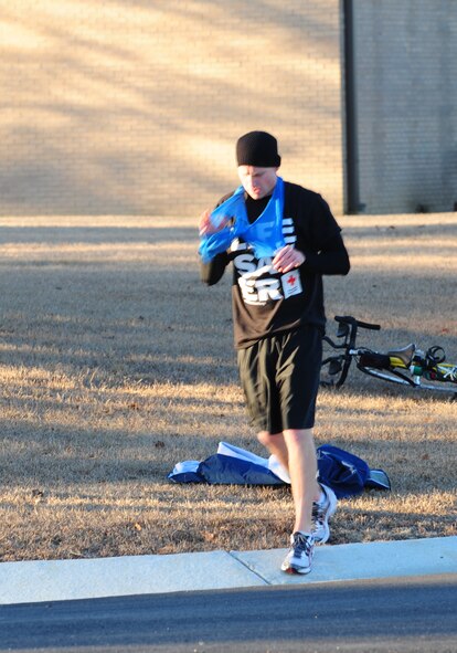 MOODY AIR FORCE BASE, Ga.-- Aaron Williams removes his outer gear as he finishes the 13 mile bike ride and begins the five kilometer run during the Polar Bear Triathlon Jan. 22. He finished second in the triathlon. (U.S. Air Force  photo/Senior Airman Stephanie Mancha)(RELEASED)