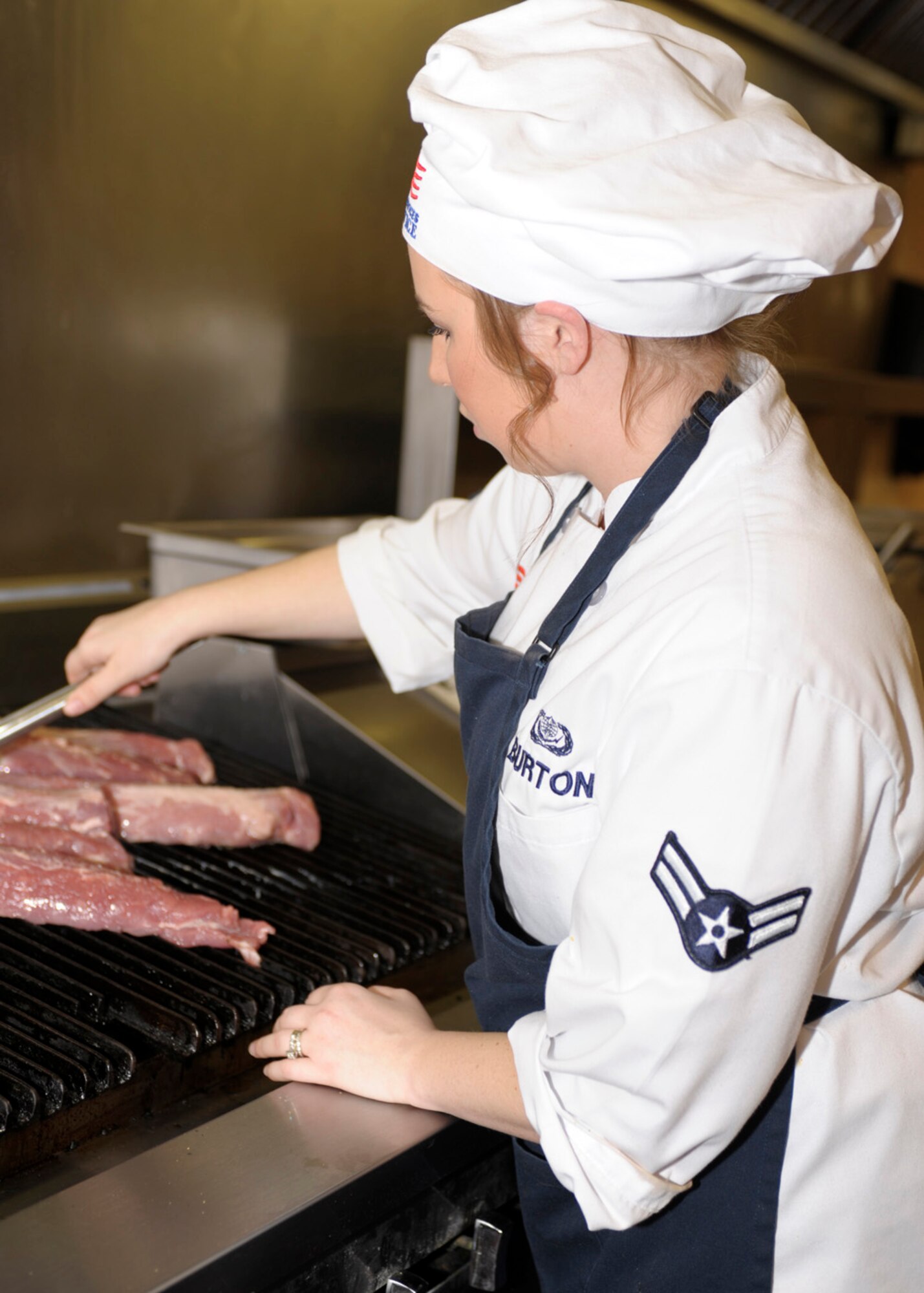 Airman 1st Class Miranda Burton, 27th Special Operations Force Support Squadron, grills sides of pork as part of the menu for the Iron Chef competition at The Landing Zone at Cannon Air Force Base, N.M., January 22. Two teams, one from The Landing Zone and the one from the Pecos Trail Dining vied for honors. The team The Landing Zone team won the event, selected by diners who attended the event. (U.S. Air Force photo by Airman Ericka Engblom)
