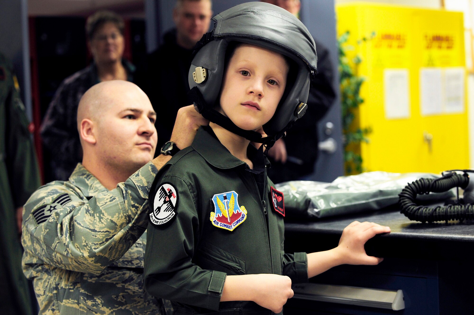 Tech. Sgt. Chris Shapiro assists Aric Lassegard, a 34th Bomb Squadron honorary aircrew member, as he puts on an HGU-55/P aircrew helmet Jan. 13, 2011, at Ellsworth Air Force Base, S.D. Members of the 34th BS gave Aric his own flight suit with a name tag and unit patches, as well as a flyer's helmet with a mask as part of the Aircrew for a Day program. Sergeant Shapiro is the 34th BS aircrew flight equipment assistant NCO in charge. (U.S. Air Force photo/Staff Sgt. Marc I. Lane)