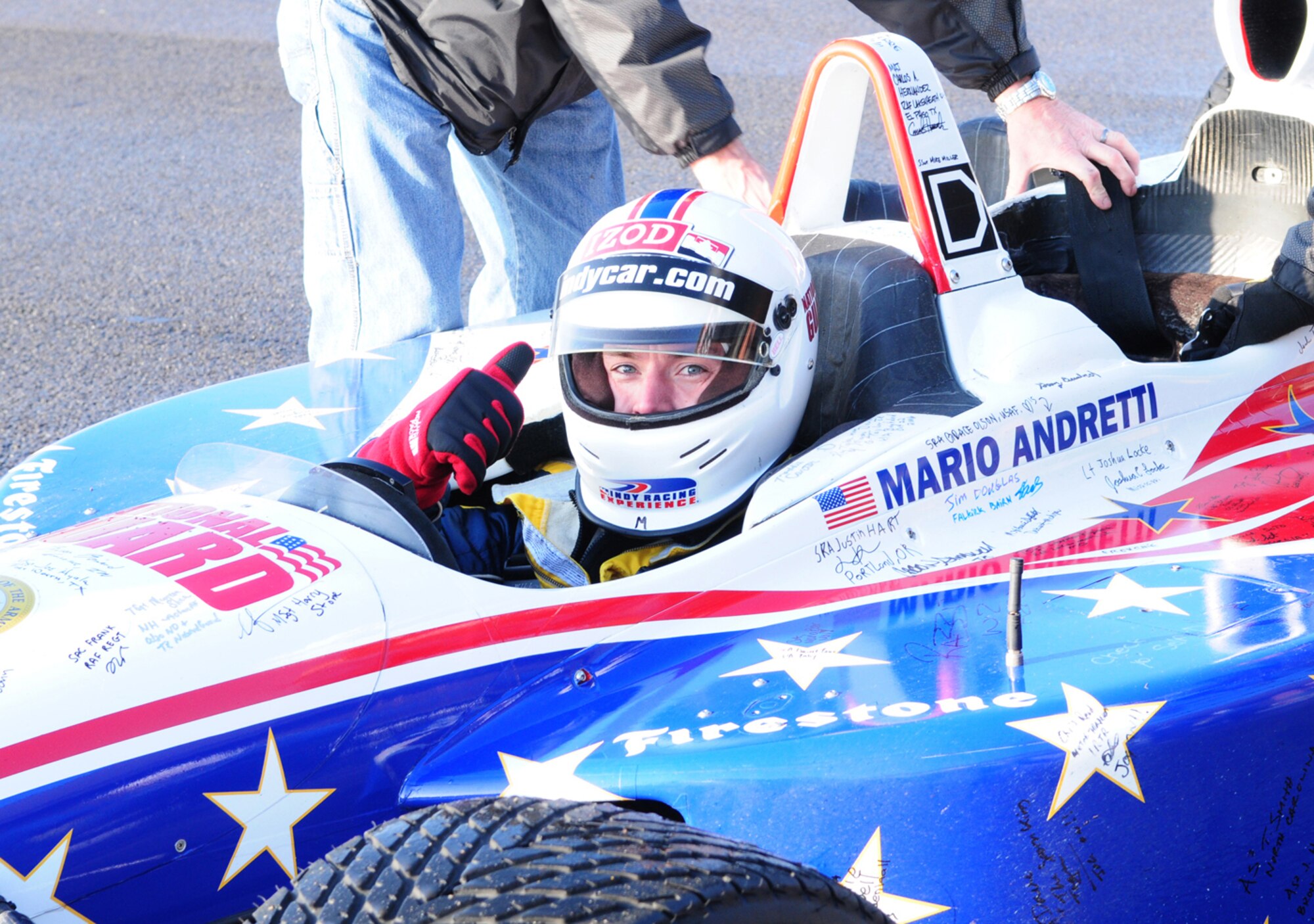 RAF MILDENHALL, England – Martin Plowman, a British driver who recently  finished his third season in the Indy Lights Series, and is getting ready to compete in his first Indy 500 race this year, gives the thumbs-up as he takes over from Mario Andretti to give RAFs Mildenhall and Lakenheath personnel a ride in a two-seater IndyCar, which travelled at up to speeds of approximately 150 mph down part of the flightline here. Mr. Plowman was one of several drivers here Jan. 21, 2011, to visit troops and raise morale. (U.S. Air Force photo/Karen Abeyasekere)