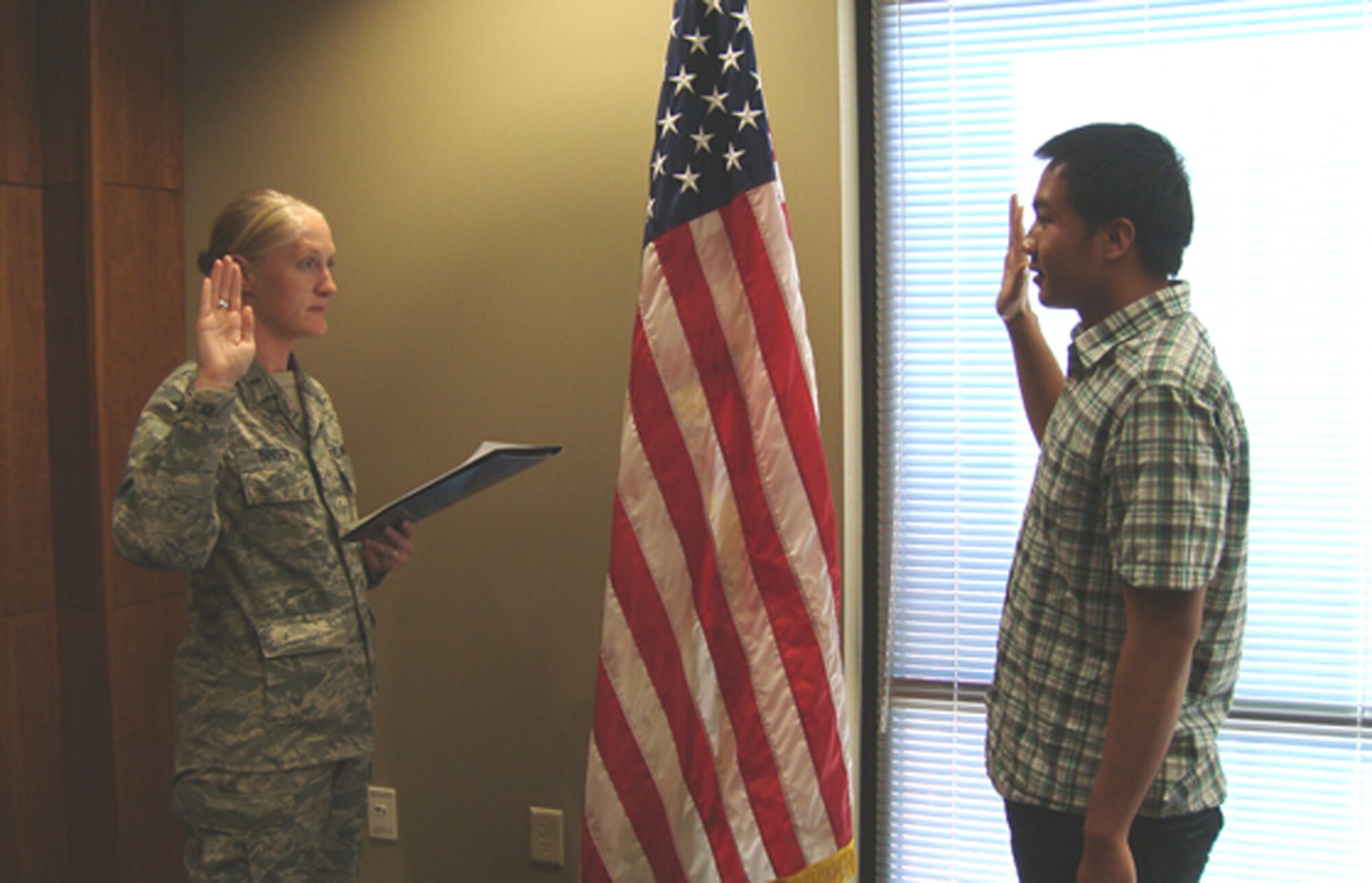 (Left) Second Lieutenant Melanie Singer administers her first enlistment oath since being commissioned to Airman First Class Michael Legaspi on Jan. 21 at Nellis Air Force Base, Nev. Airman Legaspi joined the 926th Group's new security forces squadron. (U.S. Air Force photo/Capt. Jessica Martin)