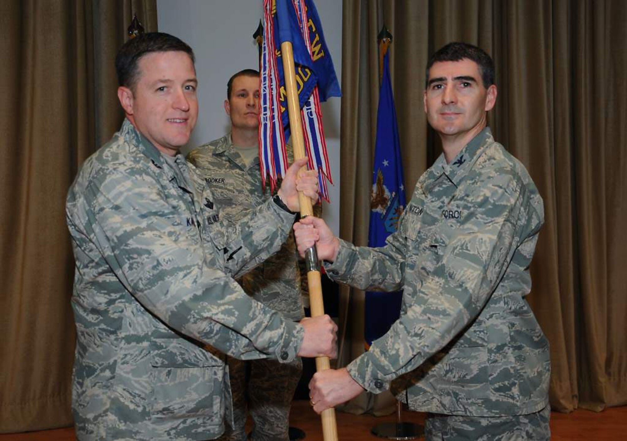 Col. Michael Katka, 386th Air Expeditionary Wing vice commander, hands the expeditionary medical group guidon to Col. Brian Stanton, the new 386th Expeditionary Medical Group commander, during a change of command ceremony at an undisclosed location Jan. 21. Colonel Stanton took over for Col. Parker Plante, who will soon be redeploying. (U.S. Air Force photo by Senior Airman Cynthia Spalding)