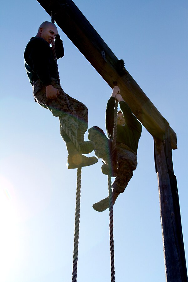 Sergeant Juan L. Garcia, drill instructor, Receiving Company, Support Battalion (left), prepares to re-enlist while  hanging from a rope on the obstacle course at Marine Corps Recruit Depot San Diego, Calif., Monday. After almost 8-years of service. Garcia said he wanted to renew his oath at the top of the rope because he wanted to do something different to  motivate other Marines. “It’s not all about the ‘Aye sir.’ It’s about enjoying what you do,” said Garcia.